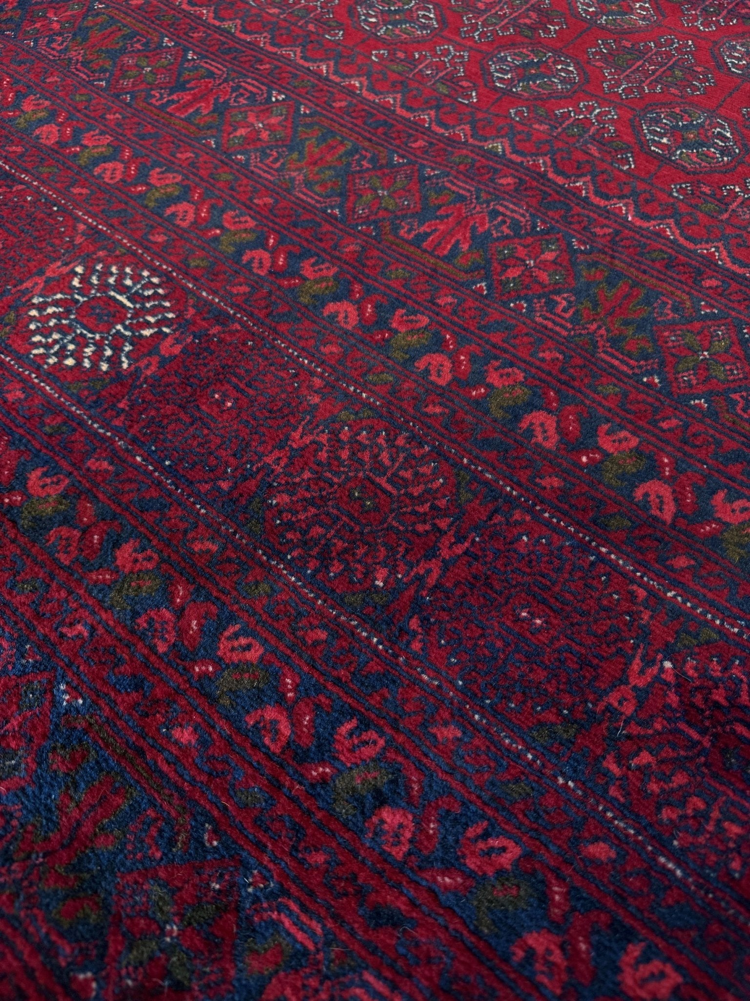 Traditional Turkmen Khoja Roshnai rug with crimson field, repeating gul motifs, navy borders, handmade merino wool area rug 7x10 with velvety pile from Indigo Rugs Burlingame Bay Area.