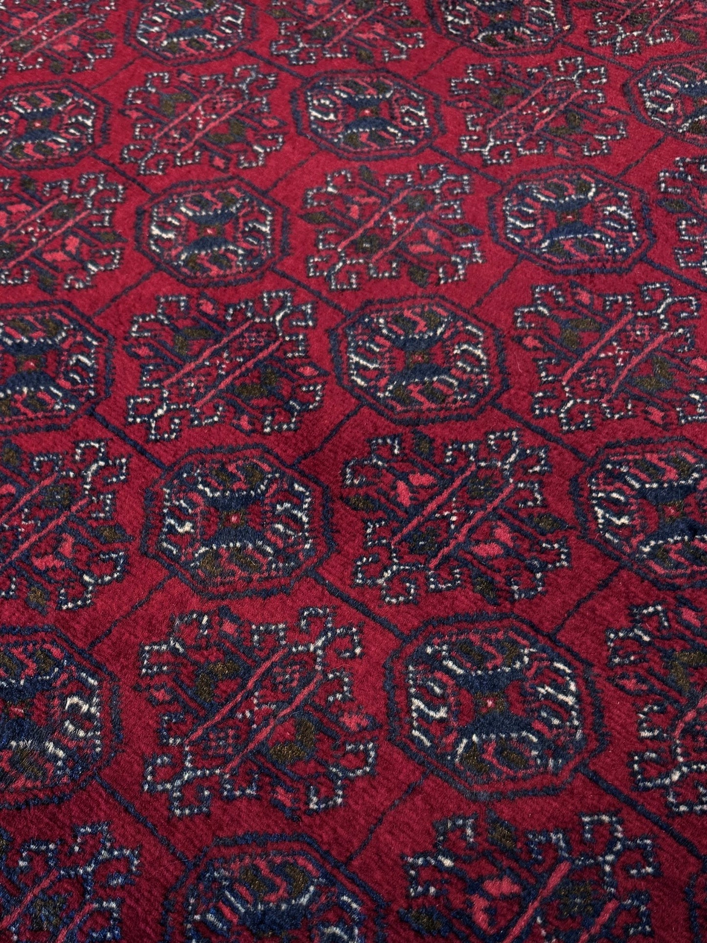 Traditional Turkmen Khoja Roshnai rug with crimson field, repeating gul motifs, navy borders, handmade merino wool area rug 7x10 with velvety pile from Indigo Rugs Burlingame Bay Area.