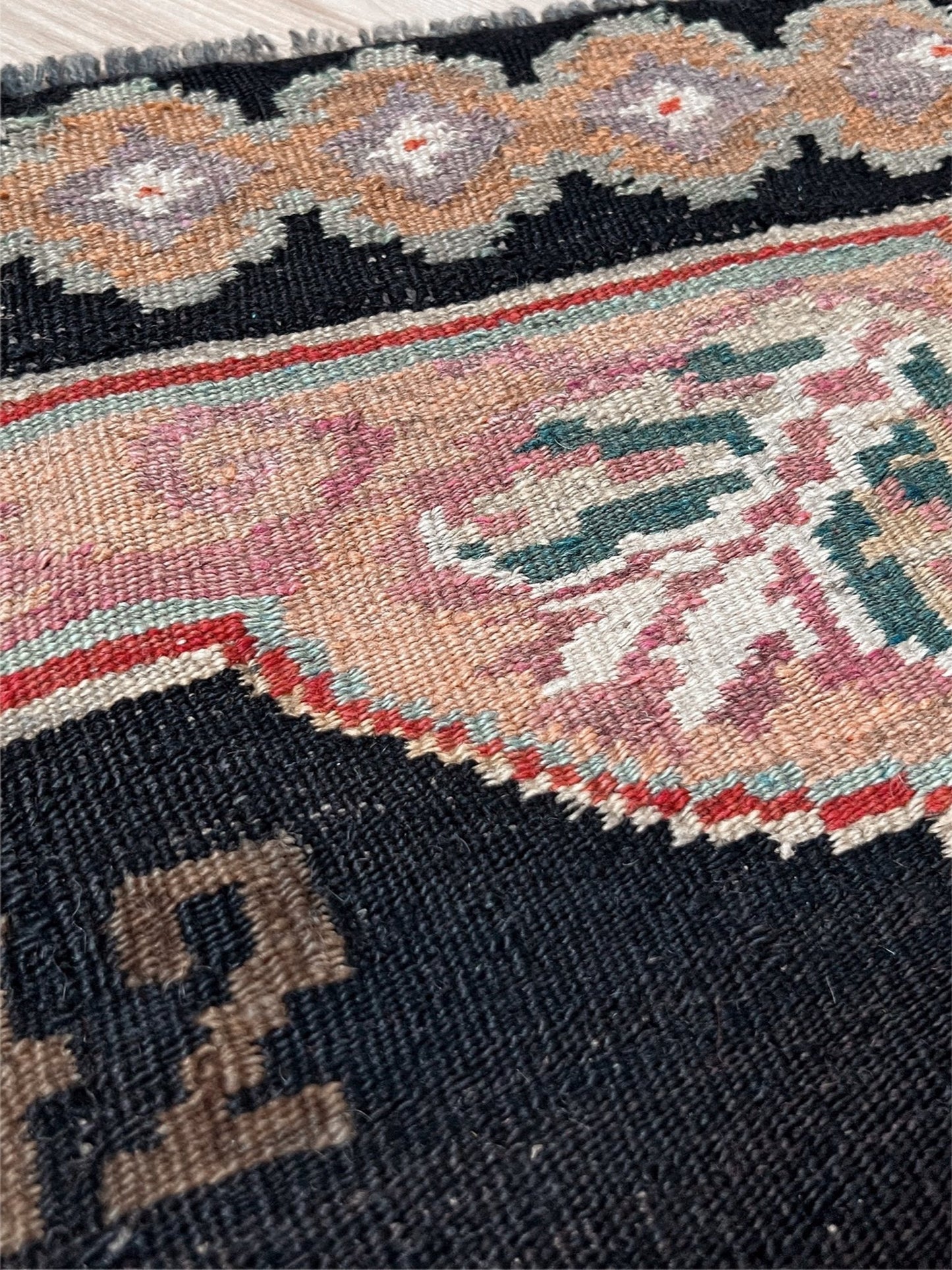 Close-up of a patterned rug with intricate designs. vintage moldovan rose kilim rug 4x7 handmade floral black field dated 1972 handmade rug san francisco bay area rug shop indigo rugs
