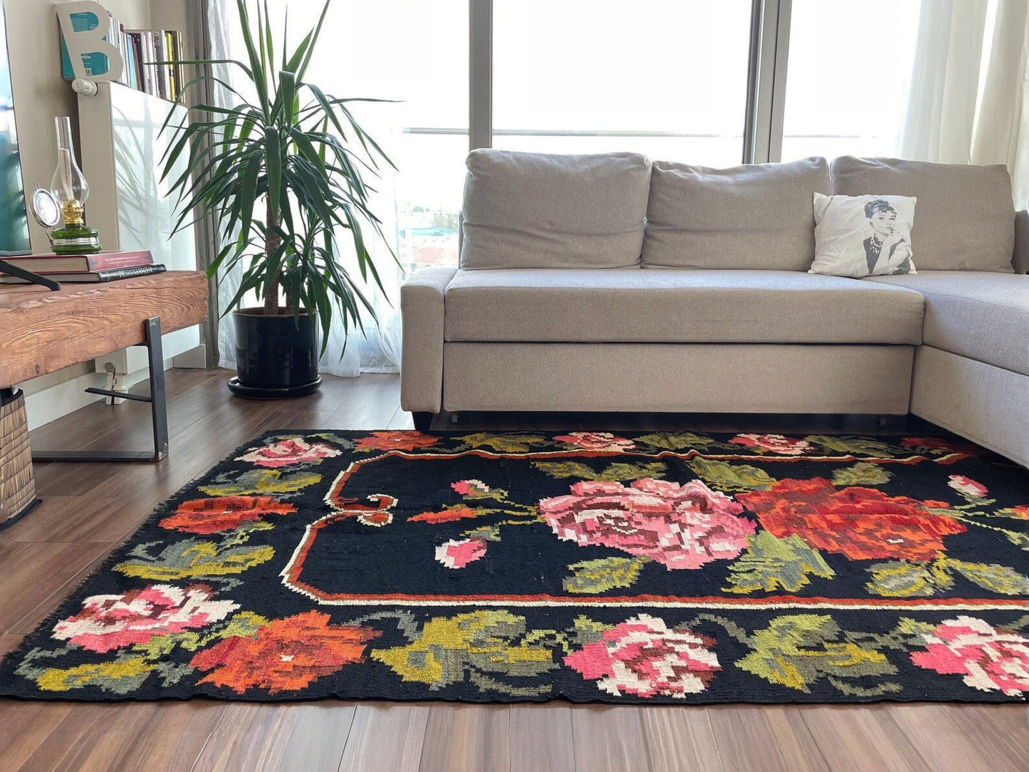 Living room with a floral rug, beige sectional sofa, and a plant. Vintage moldovan floral kilim rug 5x8 handmade rose design black background flatweave 1960s eastern european wool rug san francisco bay area rug shop indigo rugs