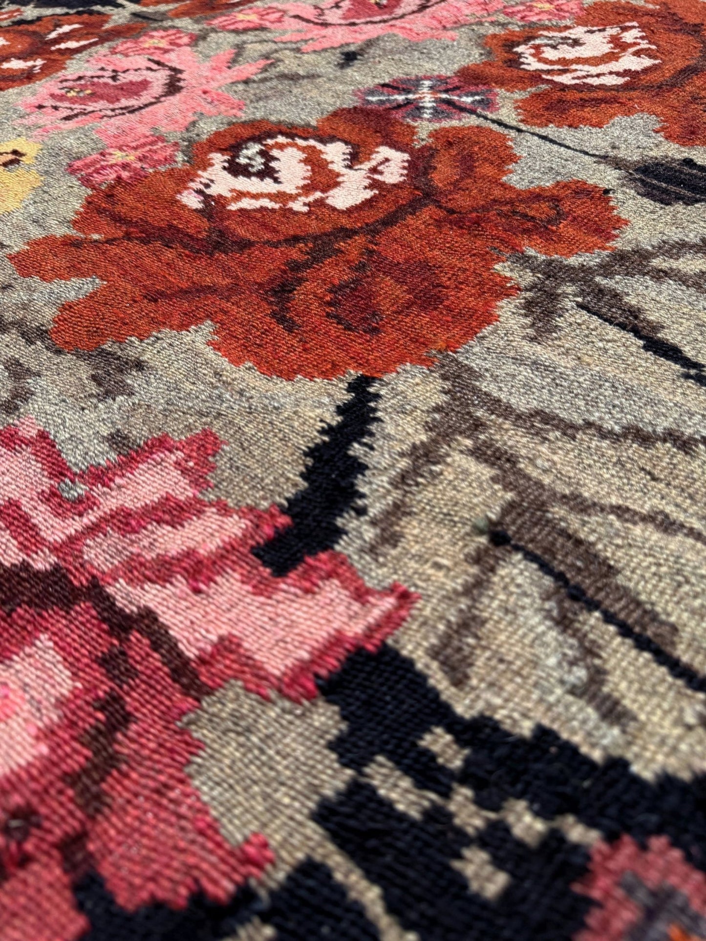 Close-up of a floral patterned moldovan rose kilim rug with red, pink, and black colors.
