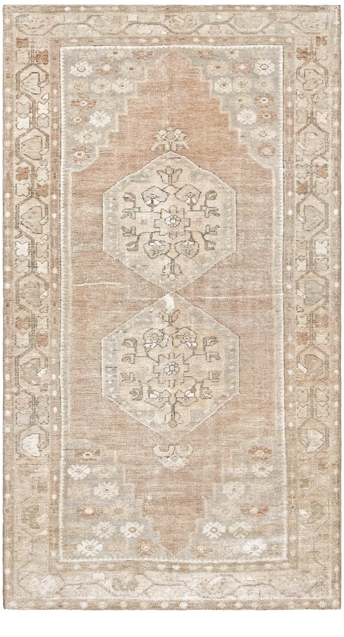 A rectangular area rug with a distressed traditional pattern in muted beige, cream, and light brown tones, featuring two central medallions and a detailed border.