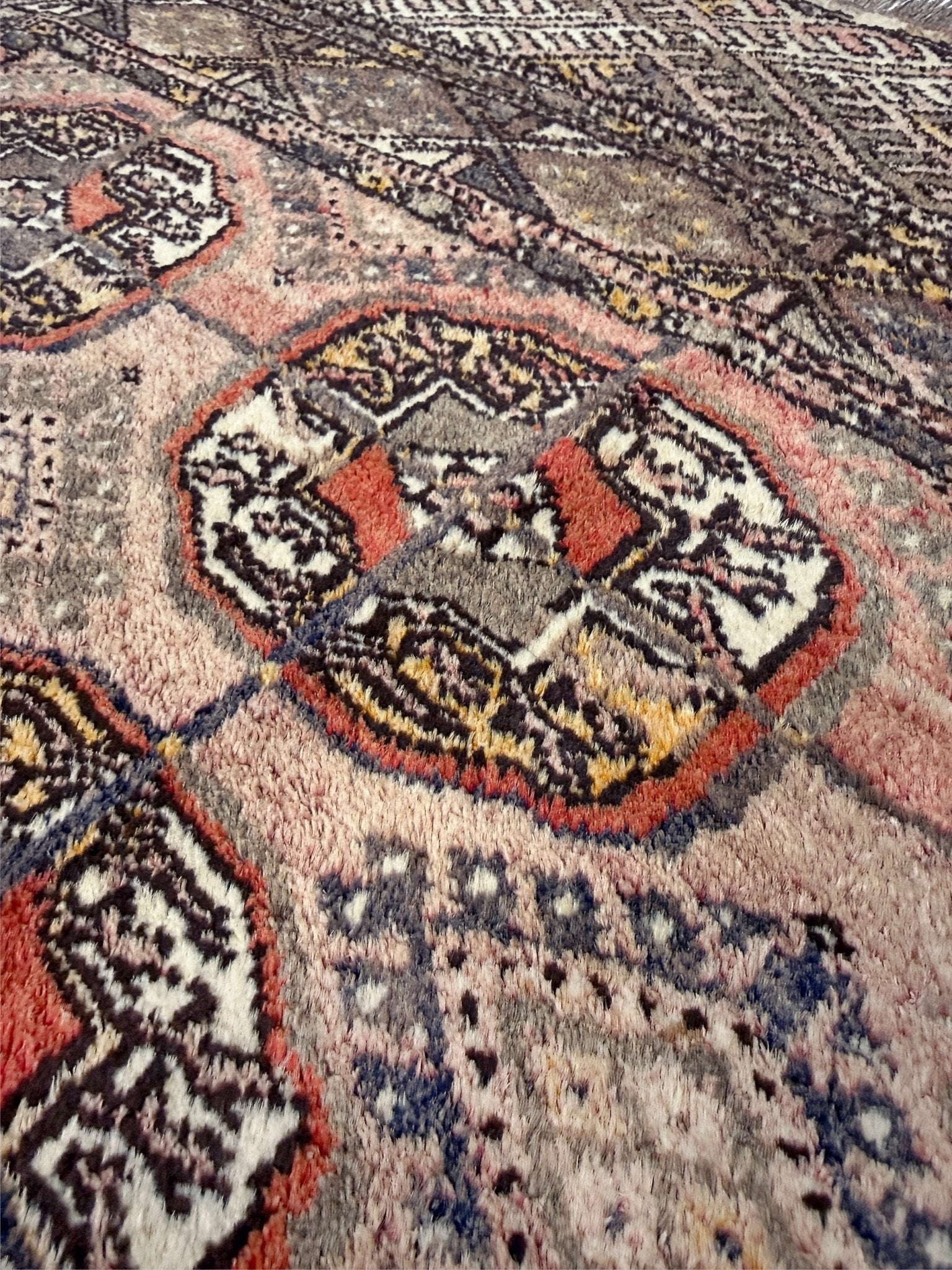 Close-up of an intricate patterned rug with geometric designs. Earthy Muted Bukhara Turkmen rug  vintage handwoven wool carpet with tribal gul motifs and aged patina, 4x5 neutral area rug for entry under desk nursery, living room, bedroom, study, office.