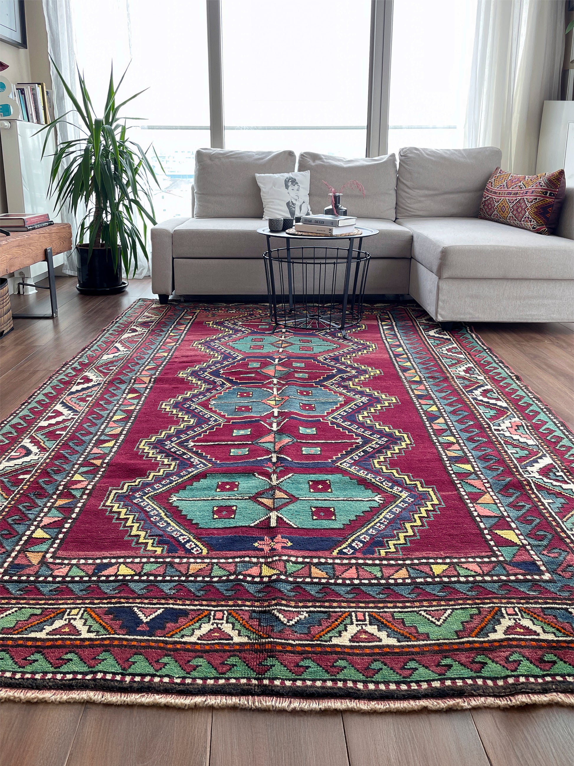 Living room with a patterned rug, sofa, and coffee table. vintage kazak caucasian rug 6x9 burgundy field tribal geometric handmade wool 1940s antique style rug san francisco bay area rug shop indigo rugs