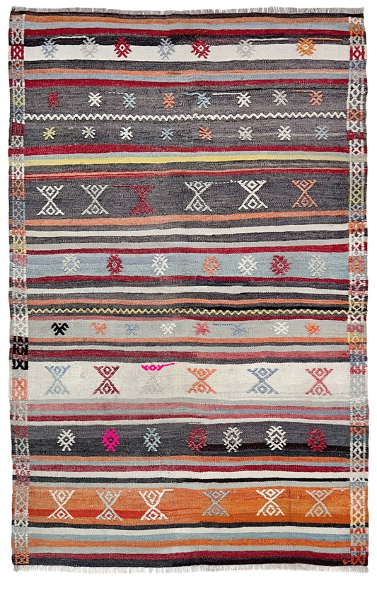 Multicolored striped rug with geometric patterns on a white background. Vintage Turkish striped kilim rug, 4x6, with tribal motifs in charcoal, ivory, sky blue, coral, and red bands.