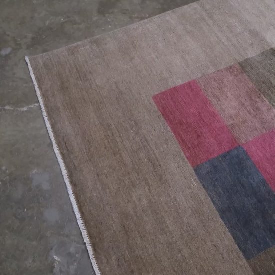 A 8x8 square handmade modern area rug featuring a central patchwork grid of multicolored textured squares on a warm taupe-beige border.