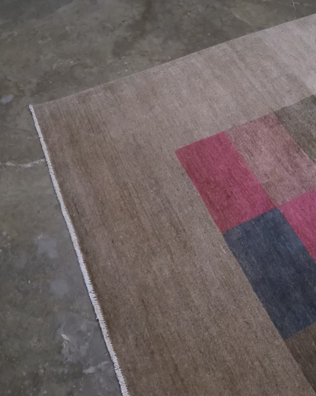 A 8x8 square handmade modern area rug featuring a central patchwork grid of multicolored textured squares on a warm taupe-beige border.