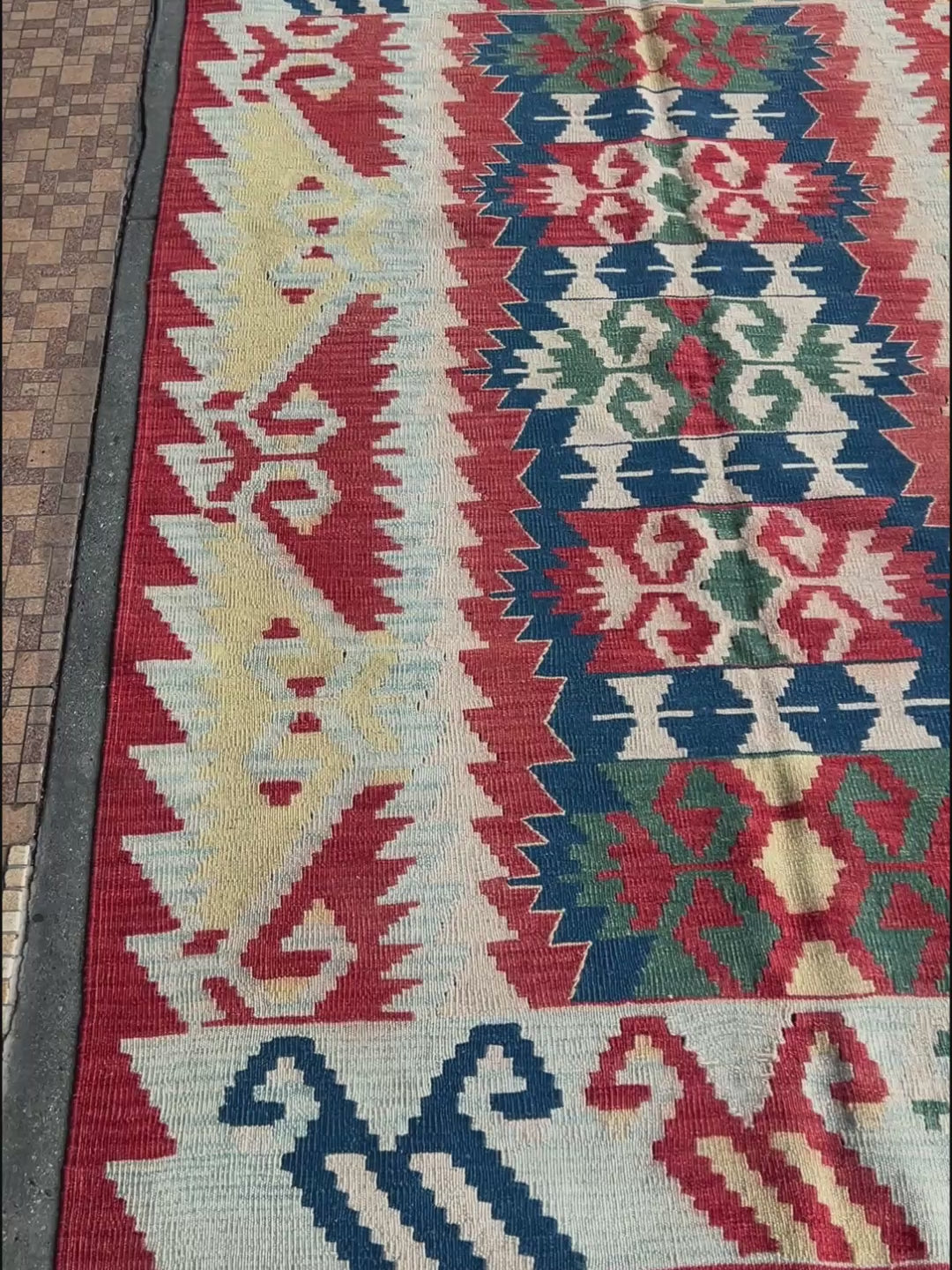 Woven turkish kilim rug with geometric pattern featuring red, blue, and beige colors. 