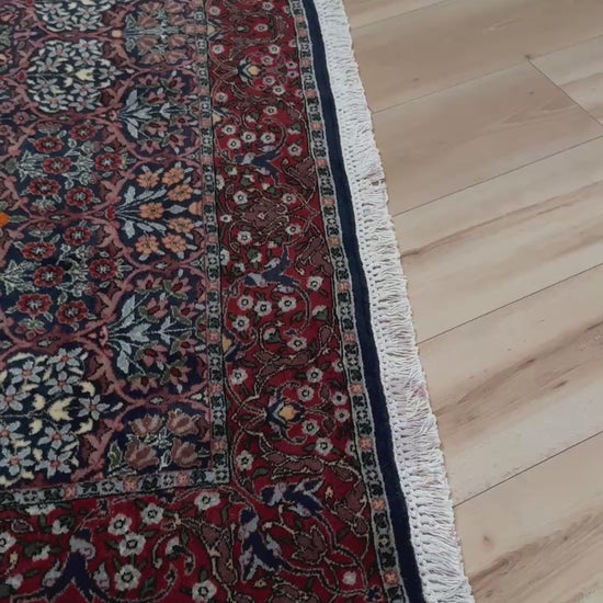 Vintage 1960s 7x9 Watermelon Hereke Turkish floral rug with midnight blue field, maroon border. Perfect for living rooms, dining spaces, or bedrooms. Indigo rug shop in Burlingame, San Francisco Bay Area, CA with free shipping.