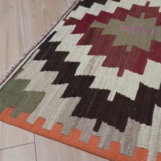 Navajo-style Mut Turkish kilim rug in earthy red, olive green, ivory, and charcoal tones, handwoven wool flatweave with bold geometric medallions, vintage tribal accent rug 2x5 for living room, bedroom, or entryway.