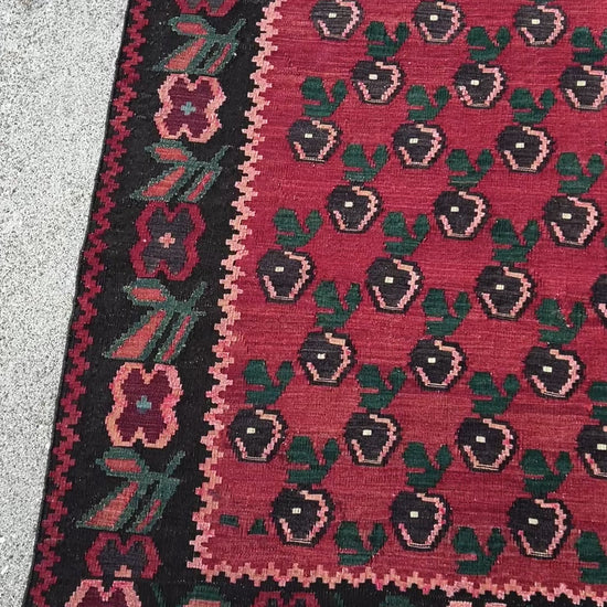 A stunning 1950s vintage Armenian Kilim flatweave rug with a crimson red backdrop, decorated with intricate floral motifs in forest green, blush pink, charcoal black, and creamy yellow accents. This handmade rug, available from the best kilim rug shop in the San Francisco Bay Area, is a versatile piece perfect for a living room, bedroom, nursery, kitchen, or dining area. Its lightweight yet durable craftsmanship makes it both a functional and decorative choice. Free shipping included!