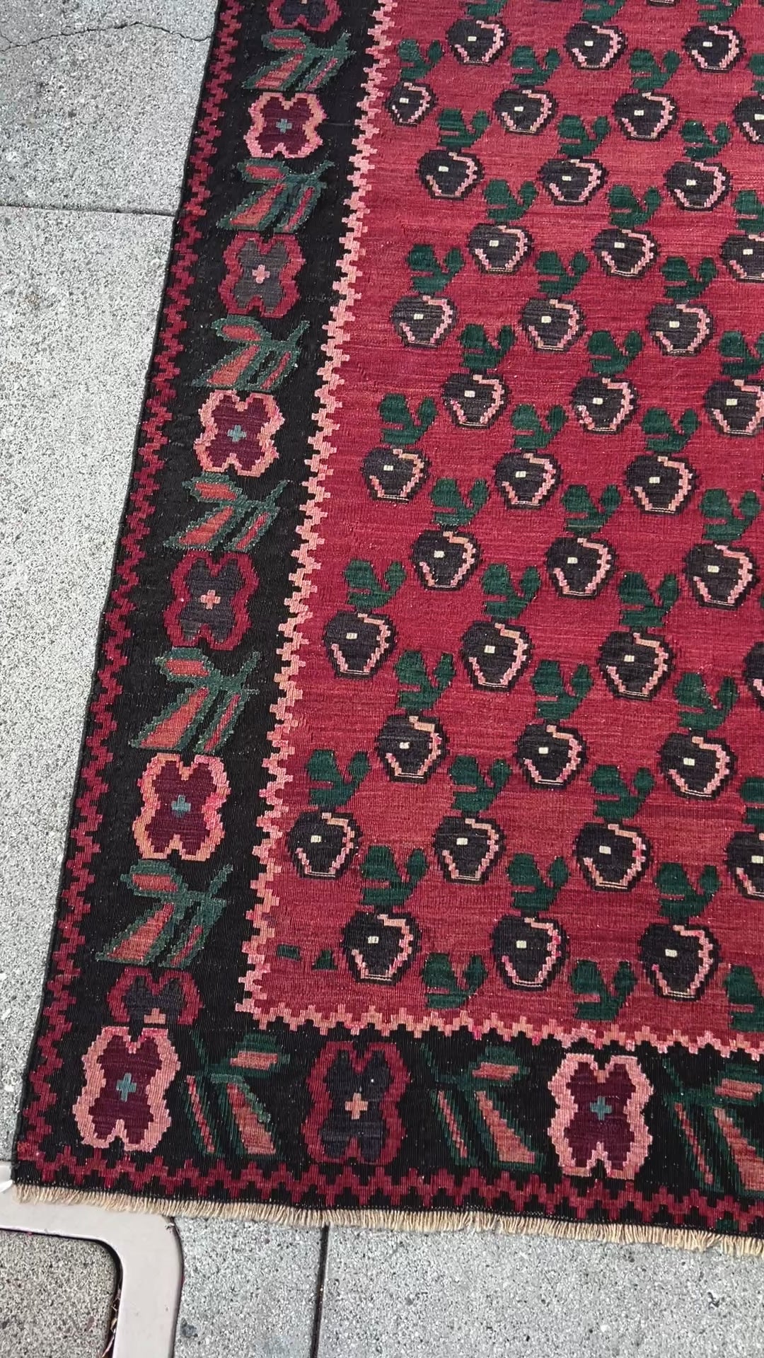 A stunning 1950s vintage Armenian Kilim flatweave rug with a crimson red backdrop, decorated with intricate floral motifs in forest green, blush pink, charcoal black, and creamy yellow accents. This handmade rug, available from the best kilim rug shop in the San Francisco Bay Area, is a versatile piece perfect for a living room, bedroom, nursery, kitchen, or dining area. Its lightweight yet durable craftsmanship makes it both a functional and decorative choice. Free shipping included!