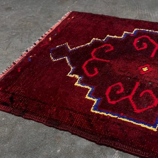Vintage Turkish Yastik rug in deep cherry red with fuchsia hot pink tribal motifs, blue outlines, and yellow highlights. Hand-knotted wool, 20x43 inches. One-of-a-kind piece from Indigo Rugs, the best rug shop in the San Francisco Bay Area (Burlingame, CA). Free shipping included.