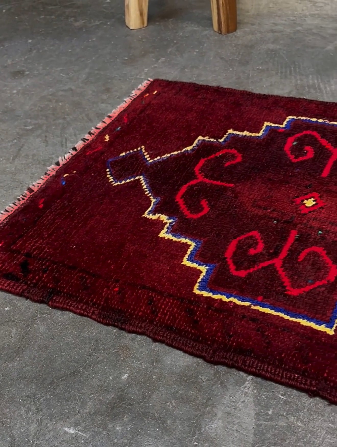 Vintage Turkish Yastik rug in deep cherry red with fuchsia hot pink tribal motifs, blue outlines, and yellow highlights. Hand-knotted wool, 20x43 inches. One-of-a-kind piece from Indigo Rugs, the best rug shop in the San Francisco Bay Area (Burlingame, CA). Free shipping included.