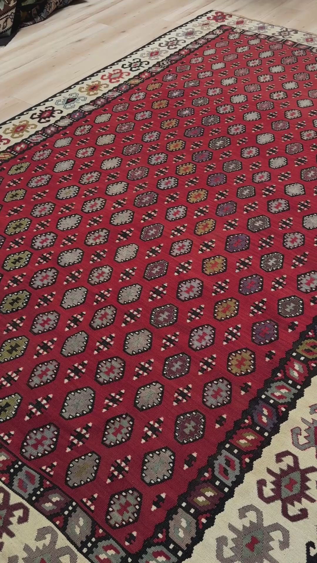 Decorative rug with intricate pattern on a red background. Vintage Pirot kilim with warm madder red field and repeating geometric medallions, handwoven wool flatweave rug with ivory border, approx. 7x10.
