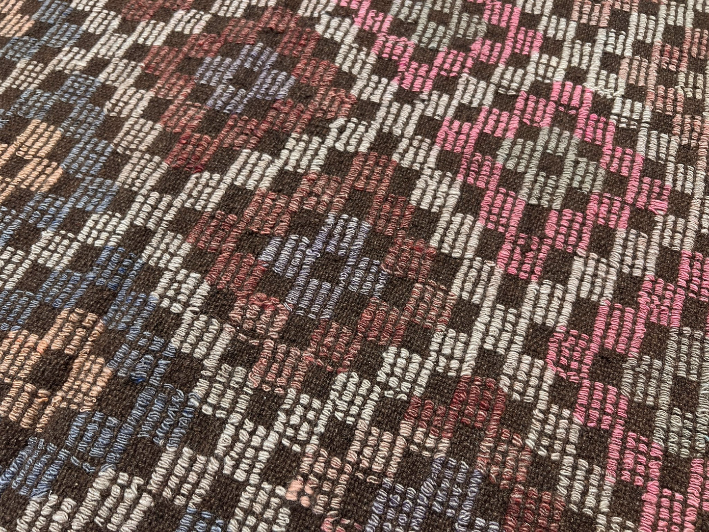 Close-up of a patterned fabric with multicolors. Earthy Vintage Turkish cicim kilim rug, 5x7 Anatolian flatweave with embroidered geometric motifs in brown, ivory, dusty rose, and slate blue