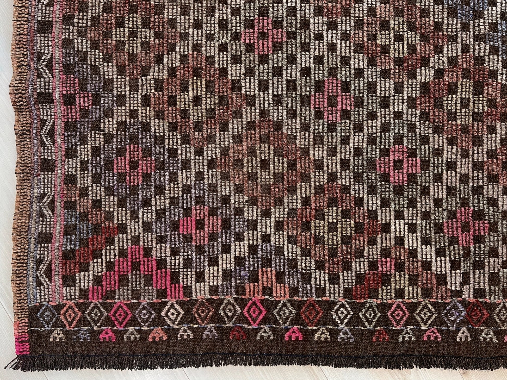 Textile with a geometric pattern featuring pink, brown, and beige colors on a white background. Earthy Vintage Turkish cicim kilim rug, 5x7 Anatolian flatweave with embroidered geometric motifs in brown, ivory, dusty rose, and slate blue