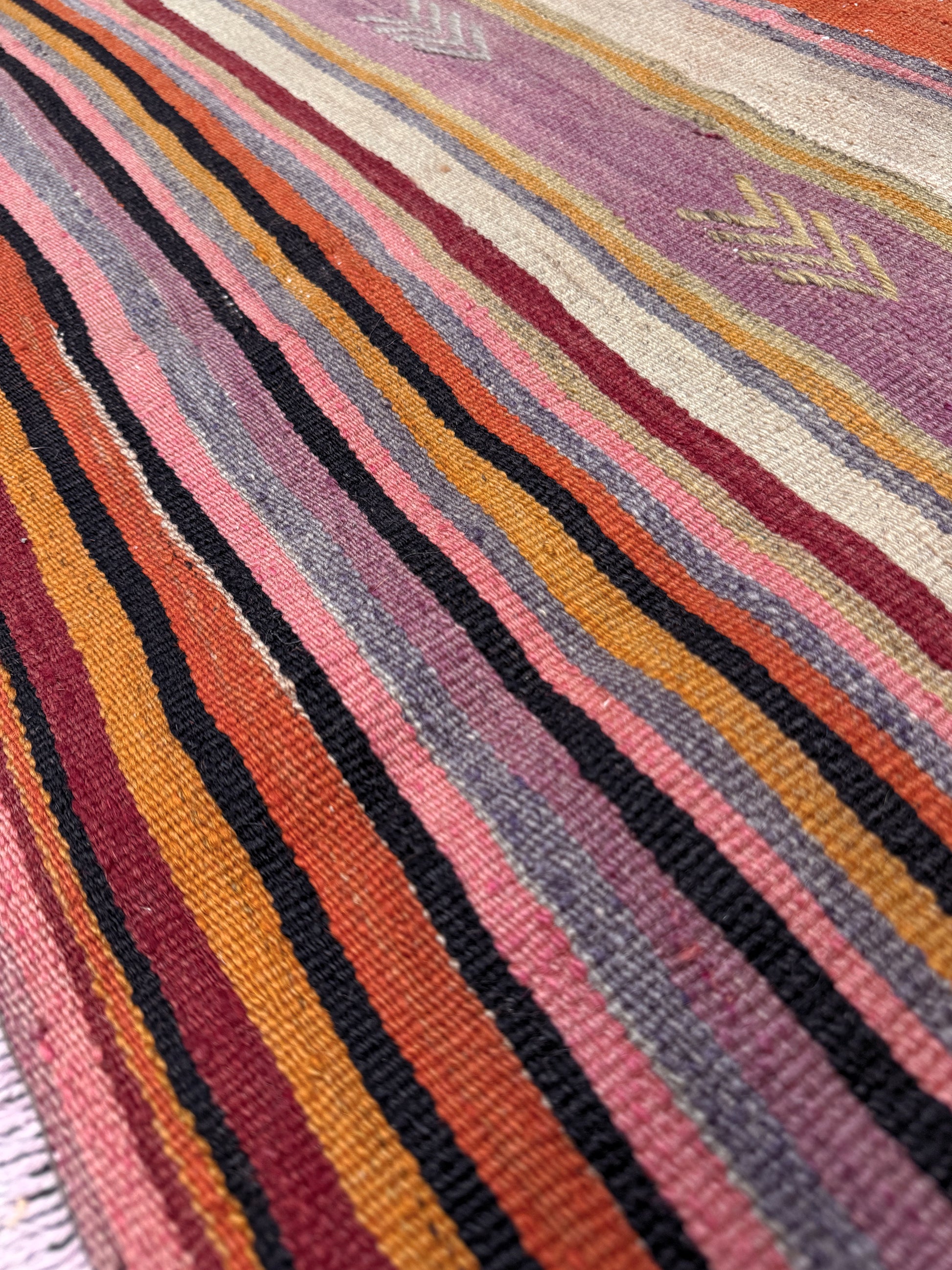 Multicolored striped pattern on a textured surface. Vintage Anatolian kilim rug, 6x8 with horizontal arrow motifs in sun-washed tones.