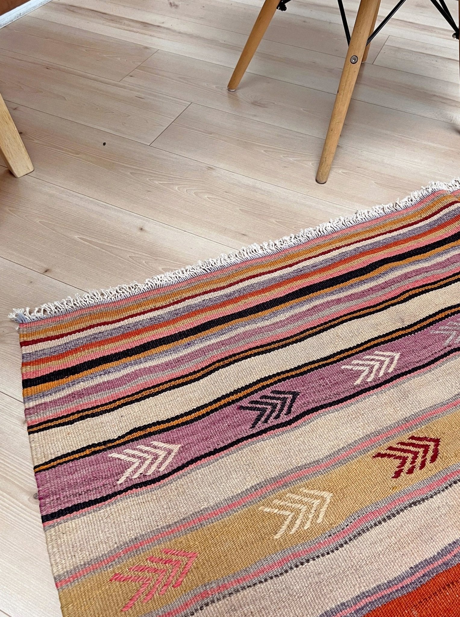 Multicolored striped rug with arrow patterns on a wooden floor. Vintage Anatolian kilim rug, 6x8 with horizontal arrow motifs in sun-washed tones.