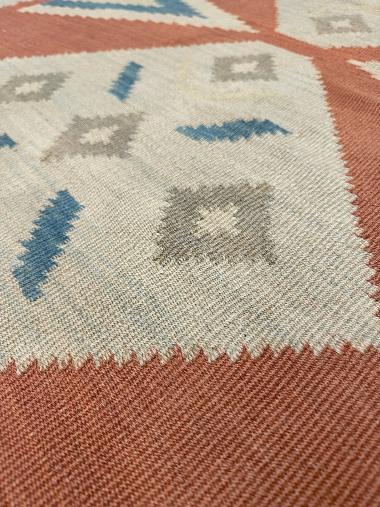 Close-up of a patterned rug with geometric design. Vintage Turkish Malatya kilim rug with coral red field and diamond medallions, handwoven Anatolian flatweave 5x8 geometric wool rug