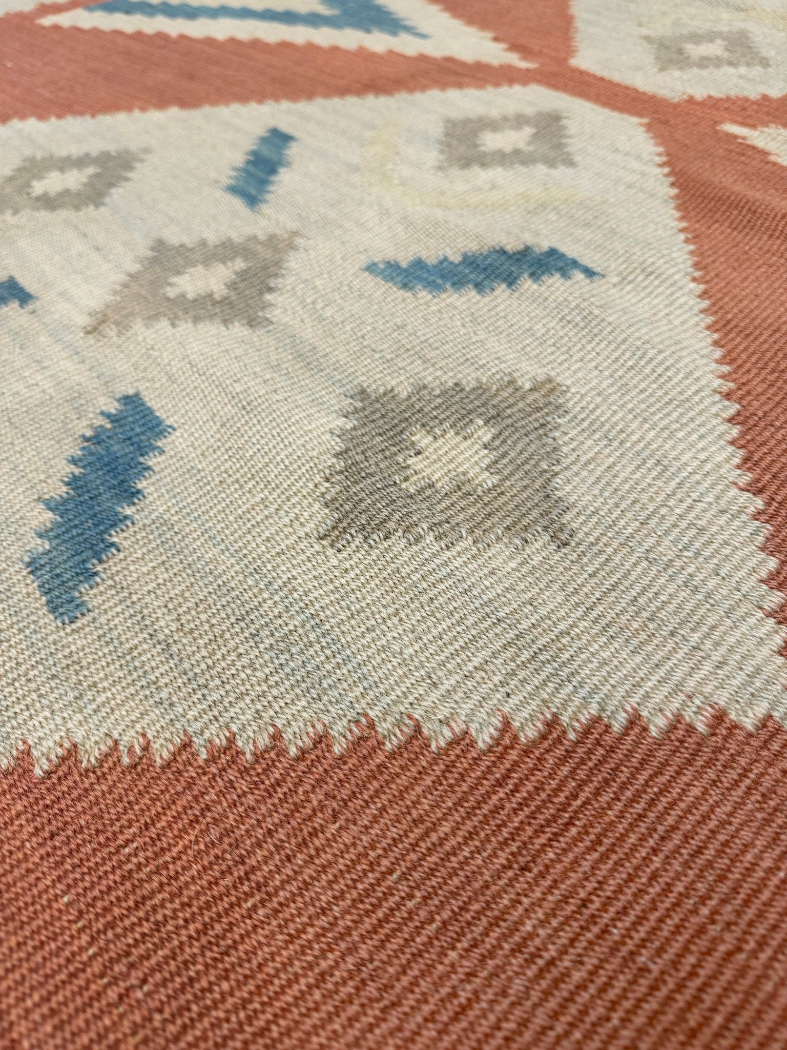 Close-up of a patterned rug with geometric design. Vintage Turkish Malatya kilim rug with coral red field and diamond medallions, handwoven Anatolian flatweave 5x8 geometric wool rug
