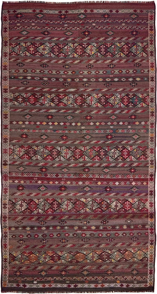 Traditional patterned rug with geometric design on a plain background. 7x13 eggplant purple oxblood red Vintage 1940s Kurdish Kars kilim rug with tribal motifs for long living rooms, hallways, great rooms, and layered interiors. From Indigo Rugs, Burlingame CA.