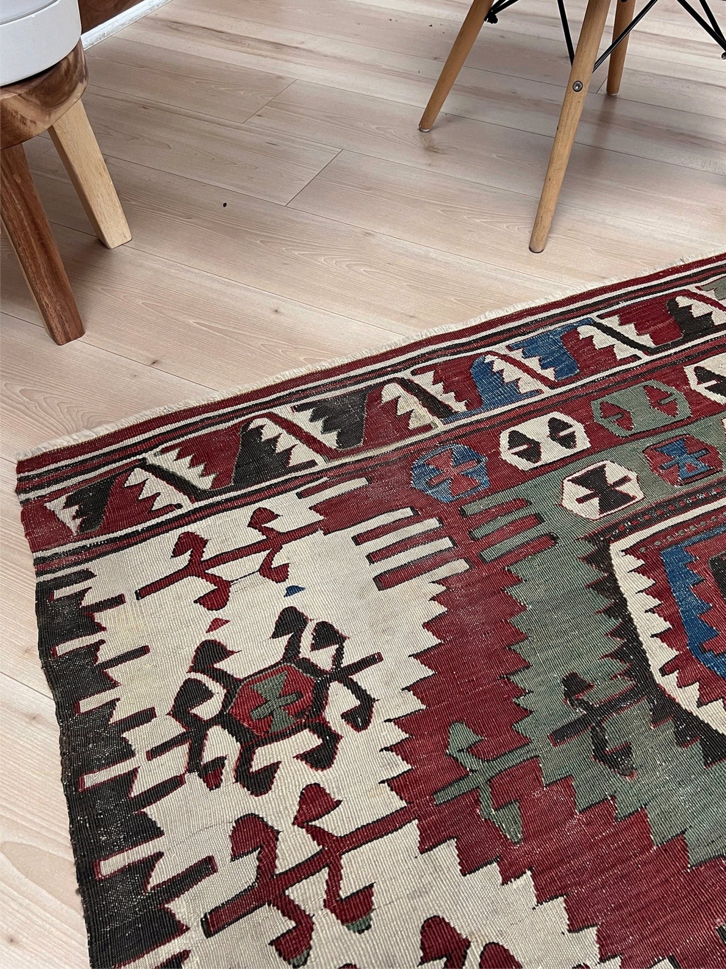 Traditional patterned rug on a wooden floor. Antique konya turkish kilim rug 6x9 vintage tribal geometric flatweave 1930s distressed handmade anatolian wool rug san francisco bay area rug shop indigo rugs