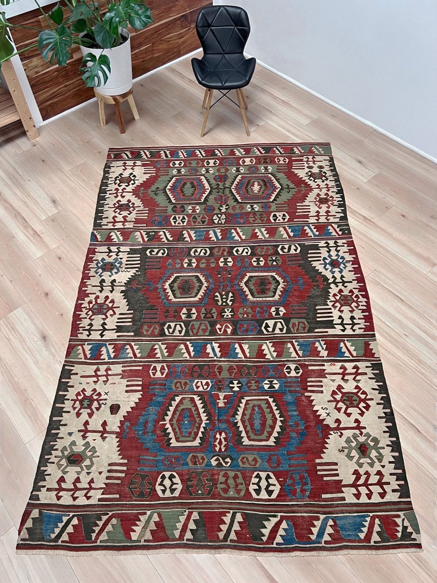 Decorative rug with geometric pattern on a wooden floor. Antique konya turkish kilim rug 6x9 vintage tribal geometric flatweave 1930s distressed handmade anatolian wool rug san francisco bay area rug shop indigo rugs