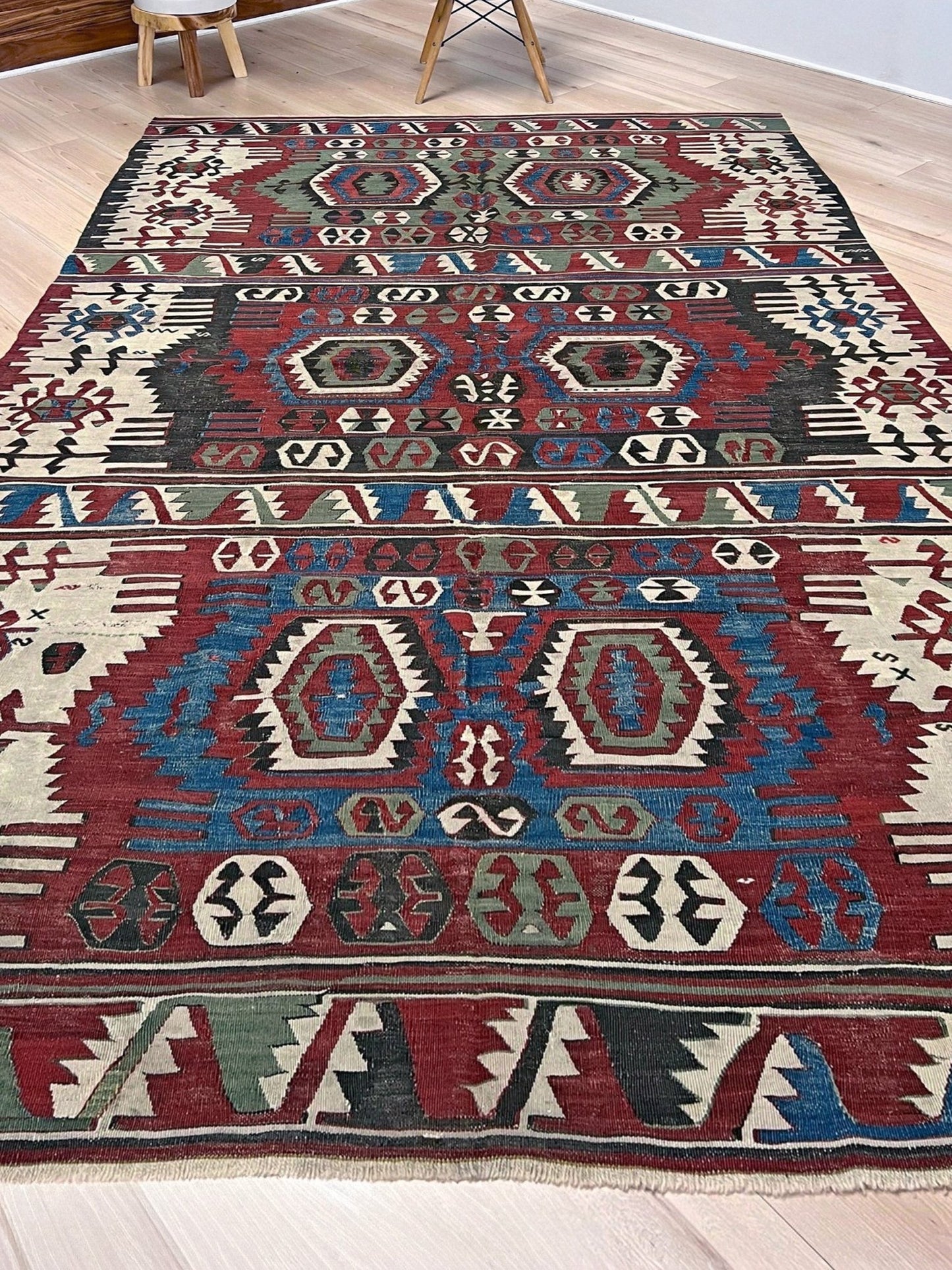 Decorative rug with geometric pattern on a wooden floor. Antique konya turkish kilim rug 6x9 vintage tribal geometric flatweave 1930s distressed handmade anatolian wool rug san francisco bay area rug shop indigo rugs