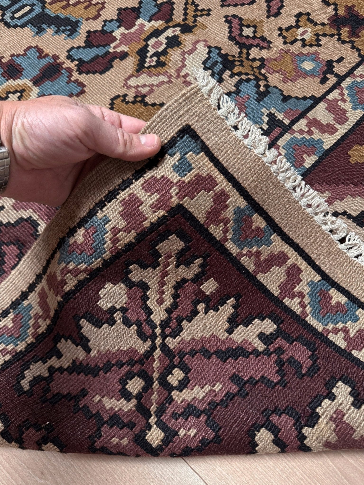 Handmade vintage Balkan floral kilim rug, approx. 8x10, with warm parchment beige field and vine-and-blossom design in dusty blue, rose, olive, and burgundy tones.