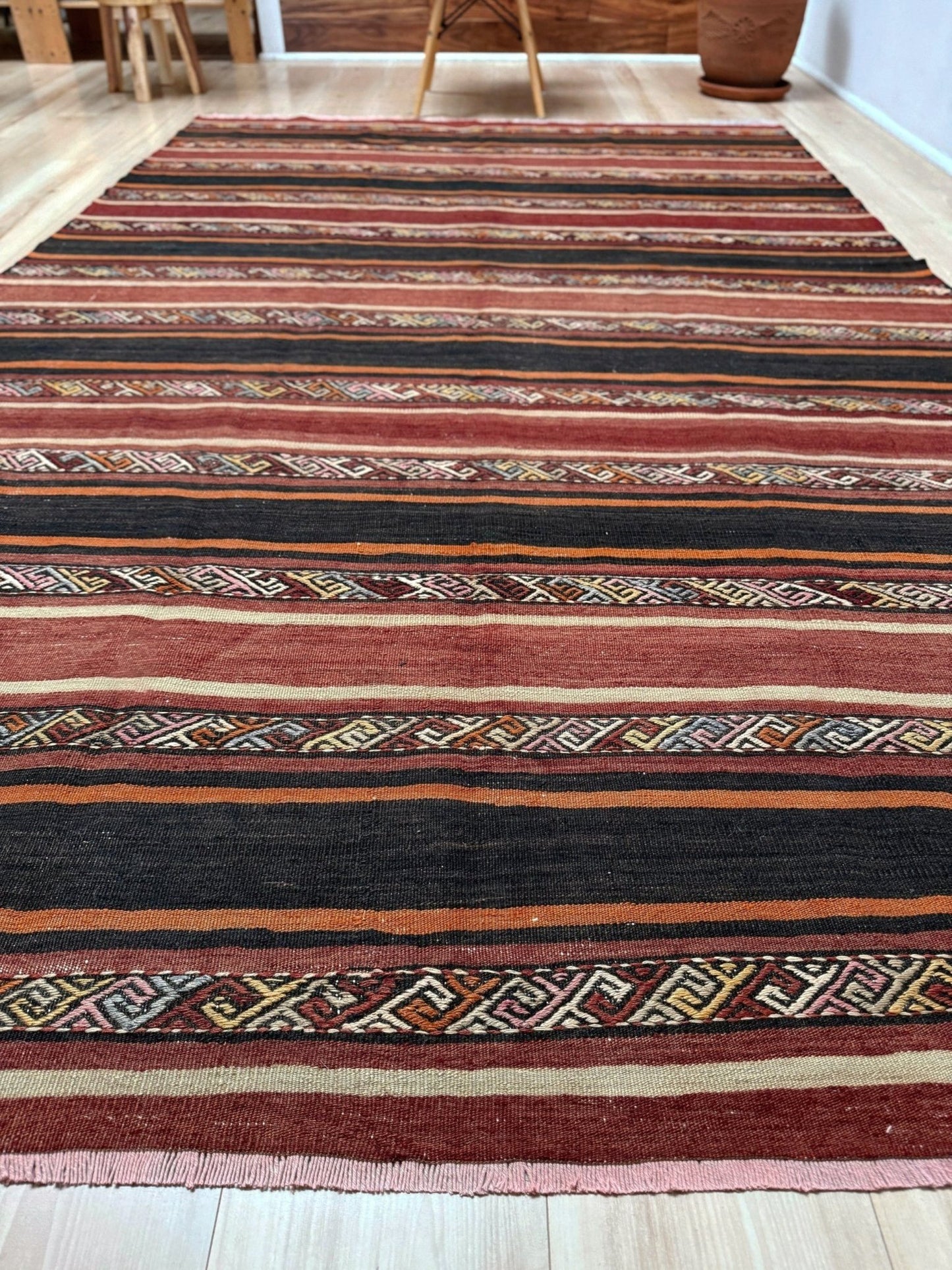 Earthy Large 6x9 vintage Turkish kilim rug with horizontal tribal stripes in madder red black and earth tones, handmade wool flatweave.