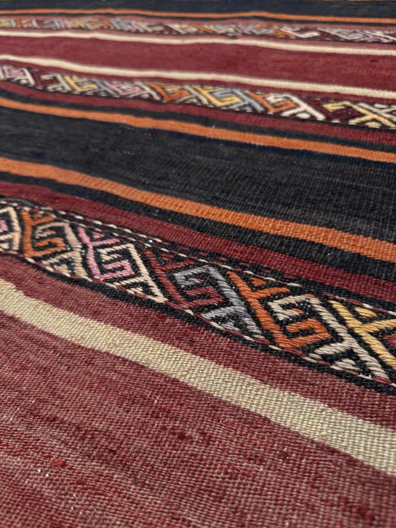 Earthy Large 6x9 vintage Turkish kilim rug with horizontal tribal stripes in madder red black and earth tones, handmade wool flatweave.
