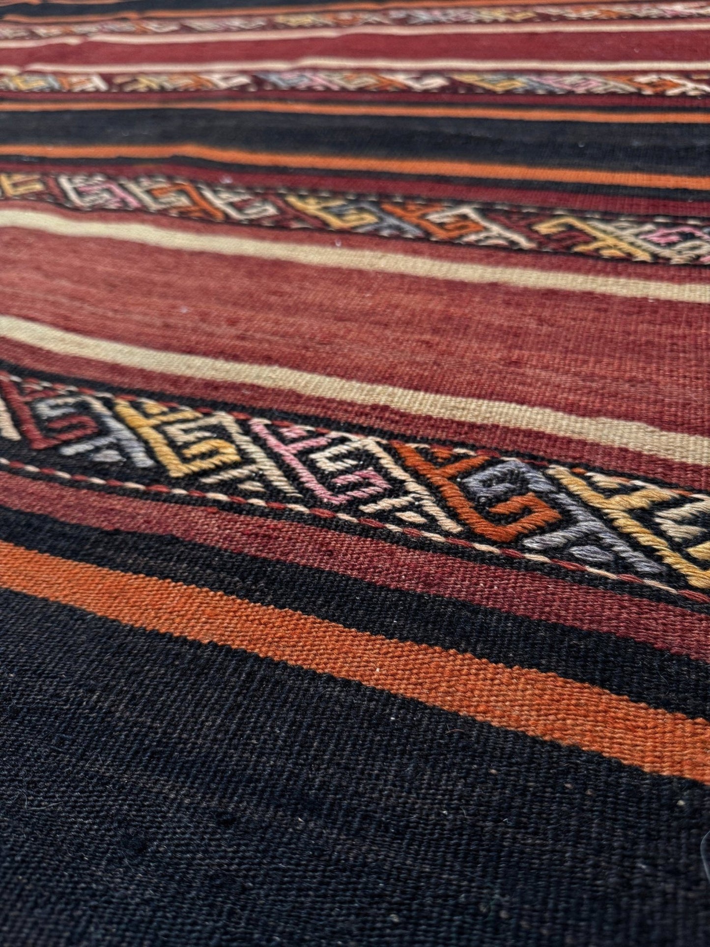 Earthy Large vintage Turkish kilim rug with horizontal tribal stripes in madder red black and earth tones, handmade wool flatweave.