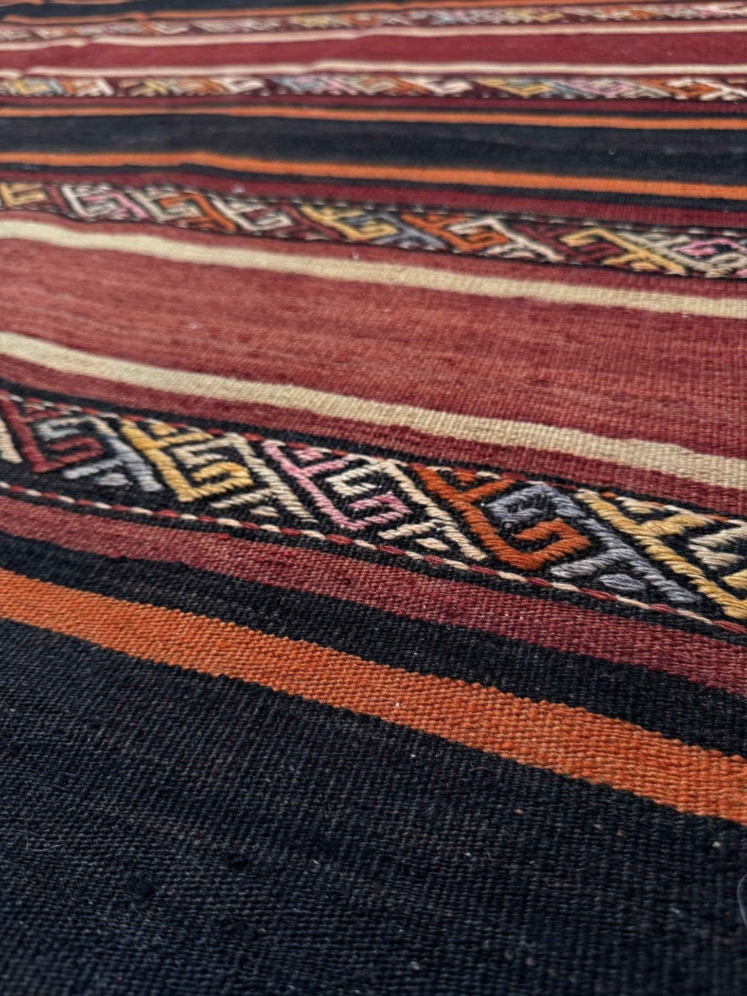 Earthy Large vintage Turkish kilim rug with horizontal tribal stripes in madder red black and earth tones, handmade wool flatweave.