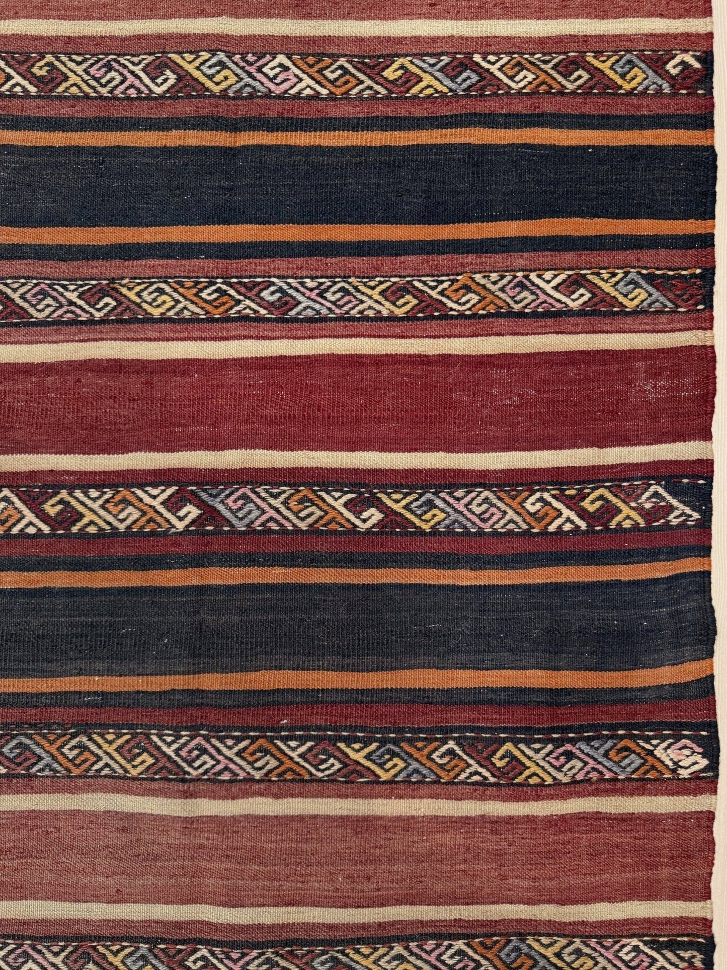 Textile with geometric pattern featuring red, blue, and orange colors. Earthy Large vintage Turkish kilim rug with horizontal tribal stripes in madder red black and earth tones, handmade wool flatweave.