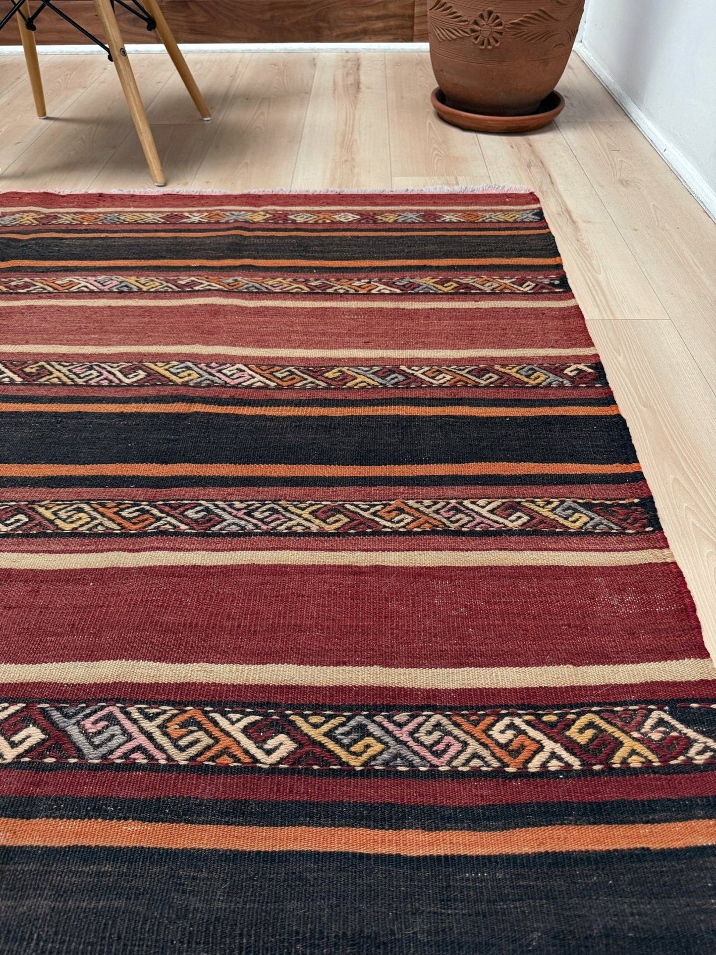 Earthy Large 6x9 vintage Turkish kilim rug with horizontal tribal stripes in madder red black and earth tones, handmade wool flatweave.