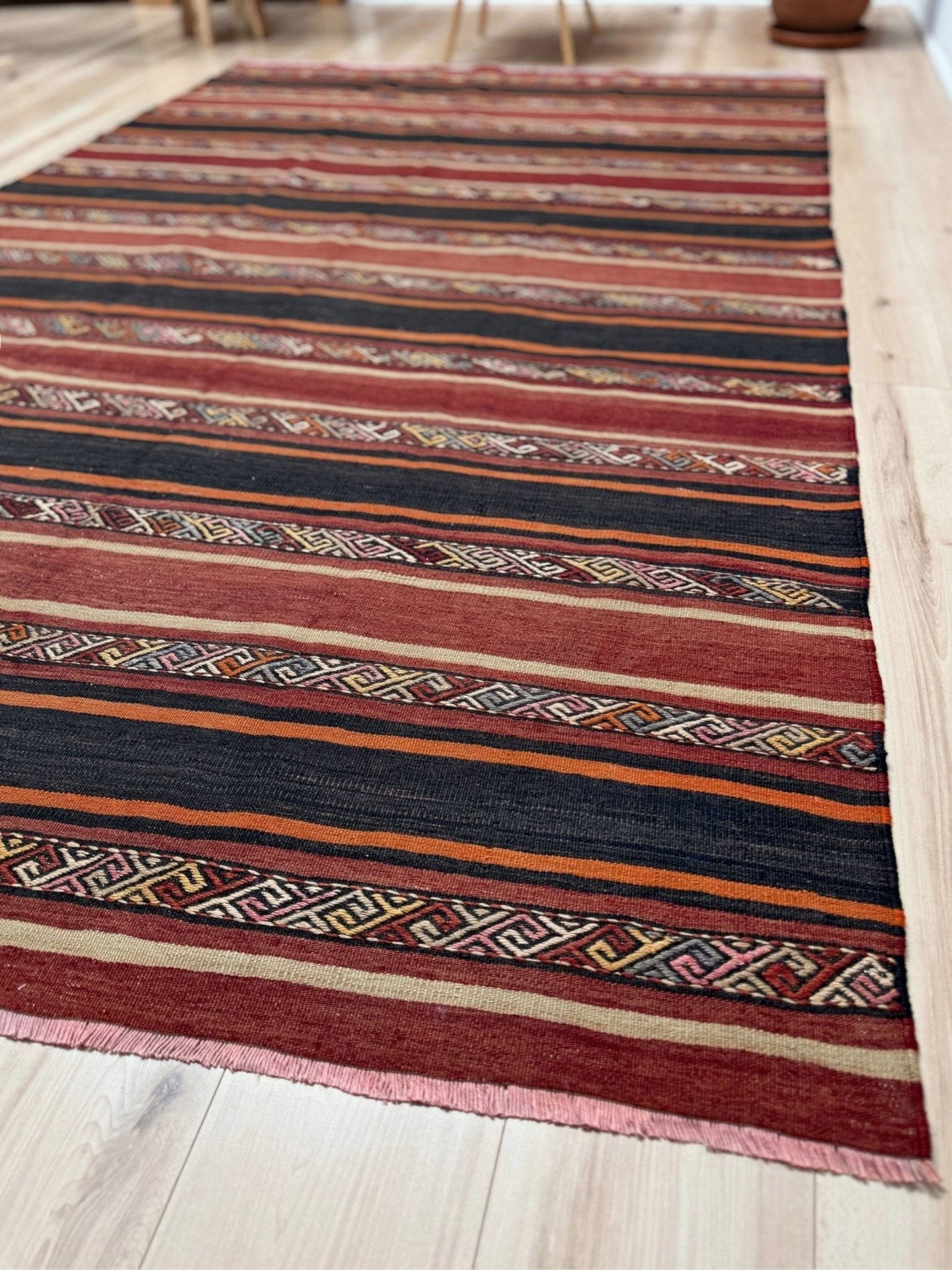 Earthy Large 6x9 vintage Turkish kilim rug with horizontal tribal stripes in madder red black and earth tones, handmade wool flatweave.