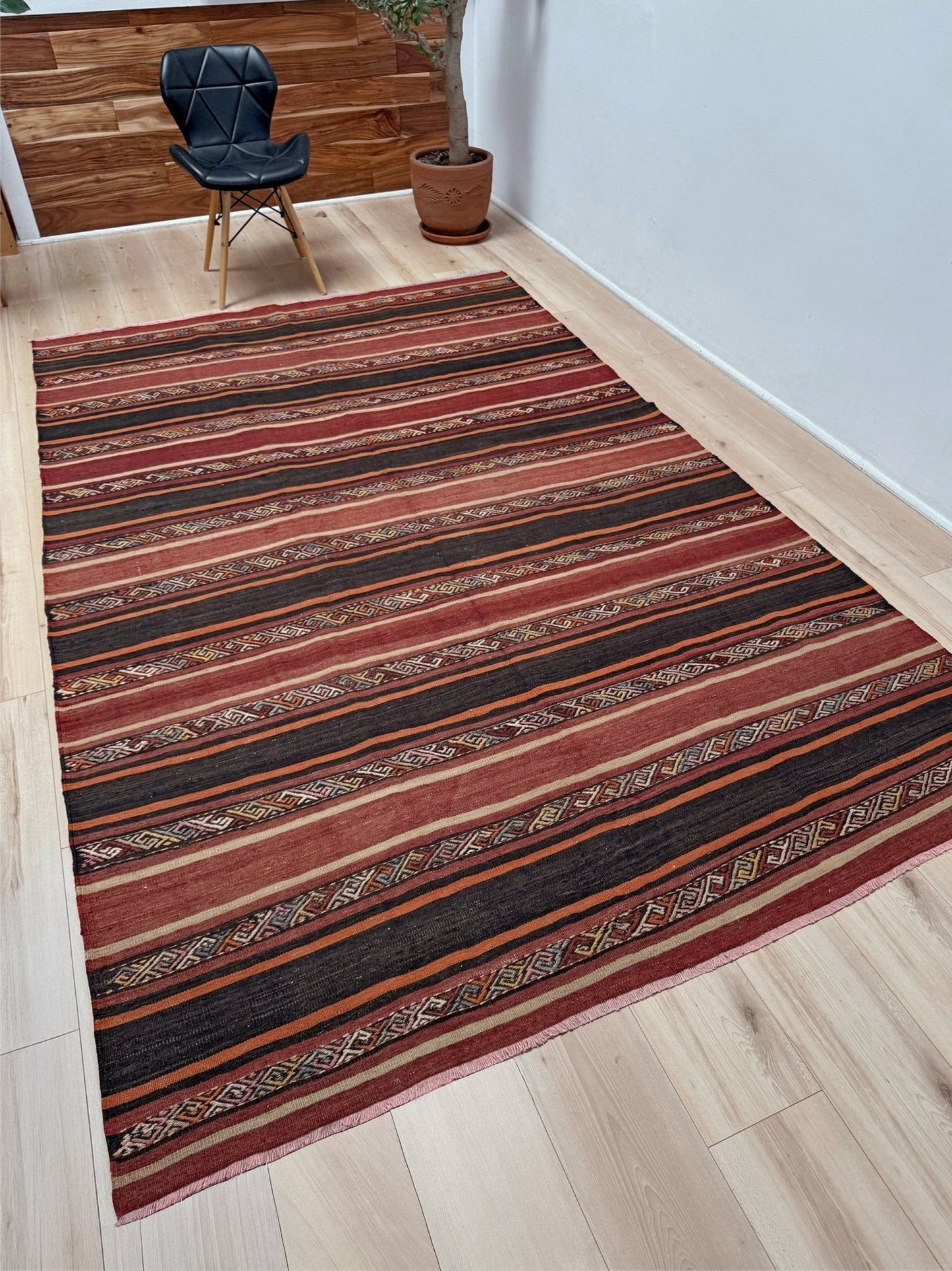 Earthy Large 6x9 vintage Turkish kilim rug with horizontal tribal stripes in madder red black and earth tones, handmade wool flatweave.