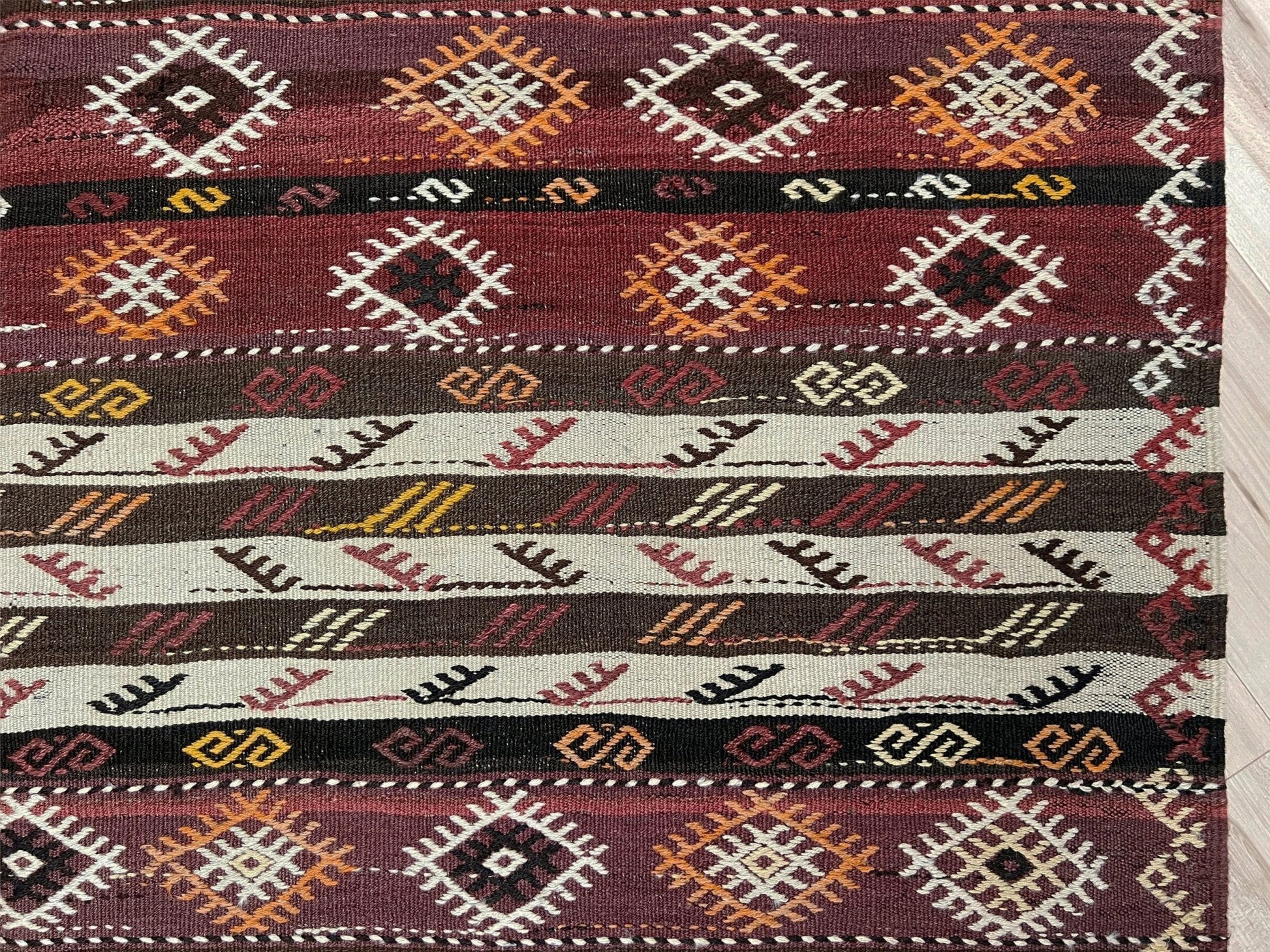 Patterned rug with geometric design on a plain background. Vintage Kars kilim rug from Eastern Turkey, 6x8, with horizontal tribal bands in brown, ivory, rust, and charcoal geometric motifs.