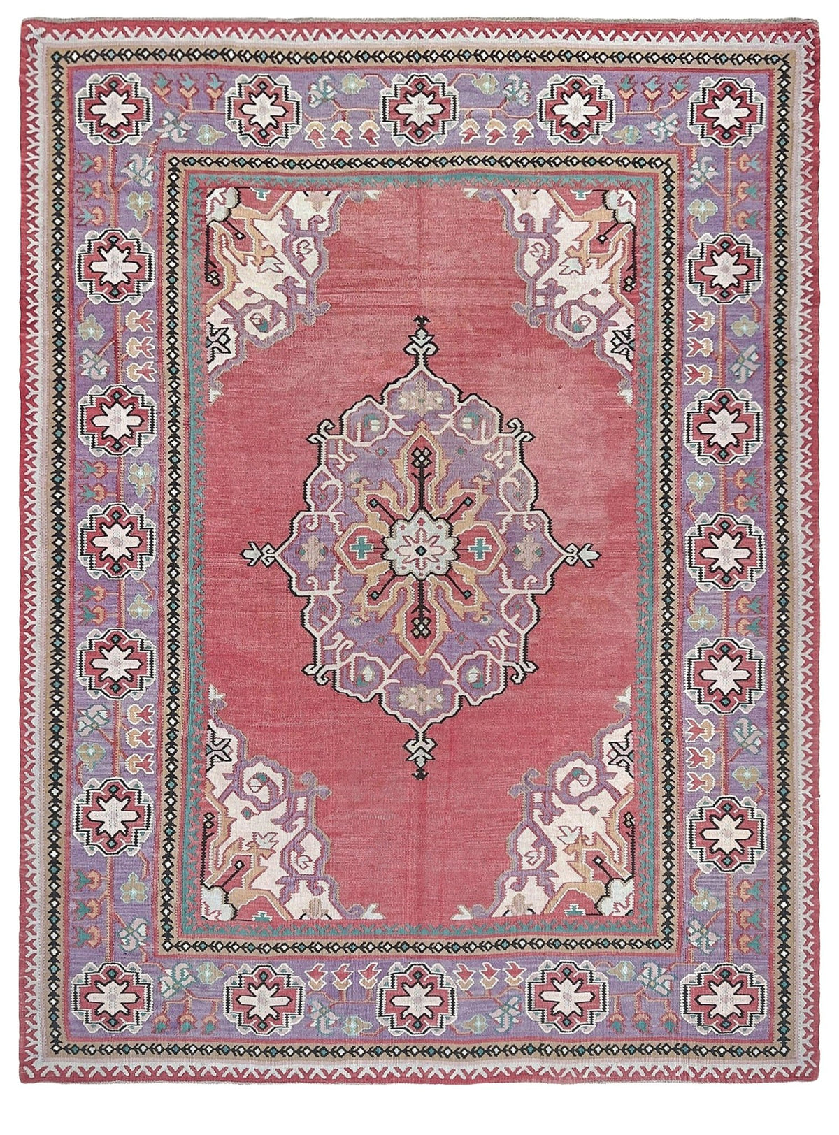 A rectangular traditional area rug with a dusty rose pink field, a central medallion, and a detailed border in muted purple, beige, and green tones.