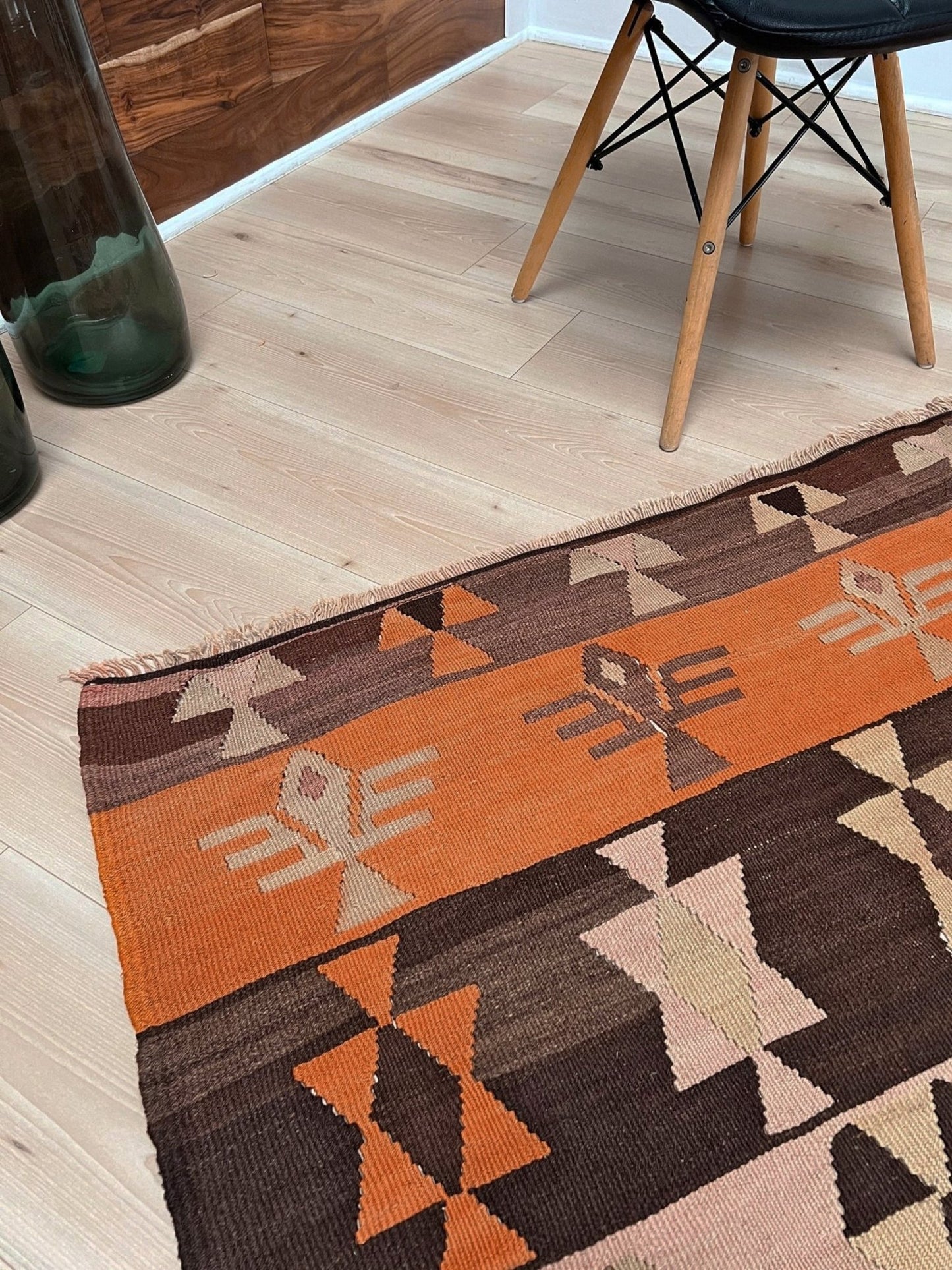 Geometric patterned rug on a wooden floor. Earthy Vintage Central Anatolian Turkish kilim rug, 6x8 with horizontal tribal bands and geometric motifs. 