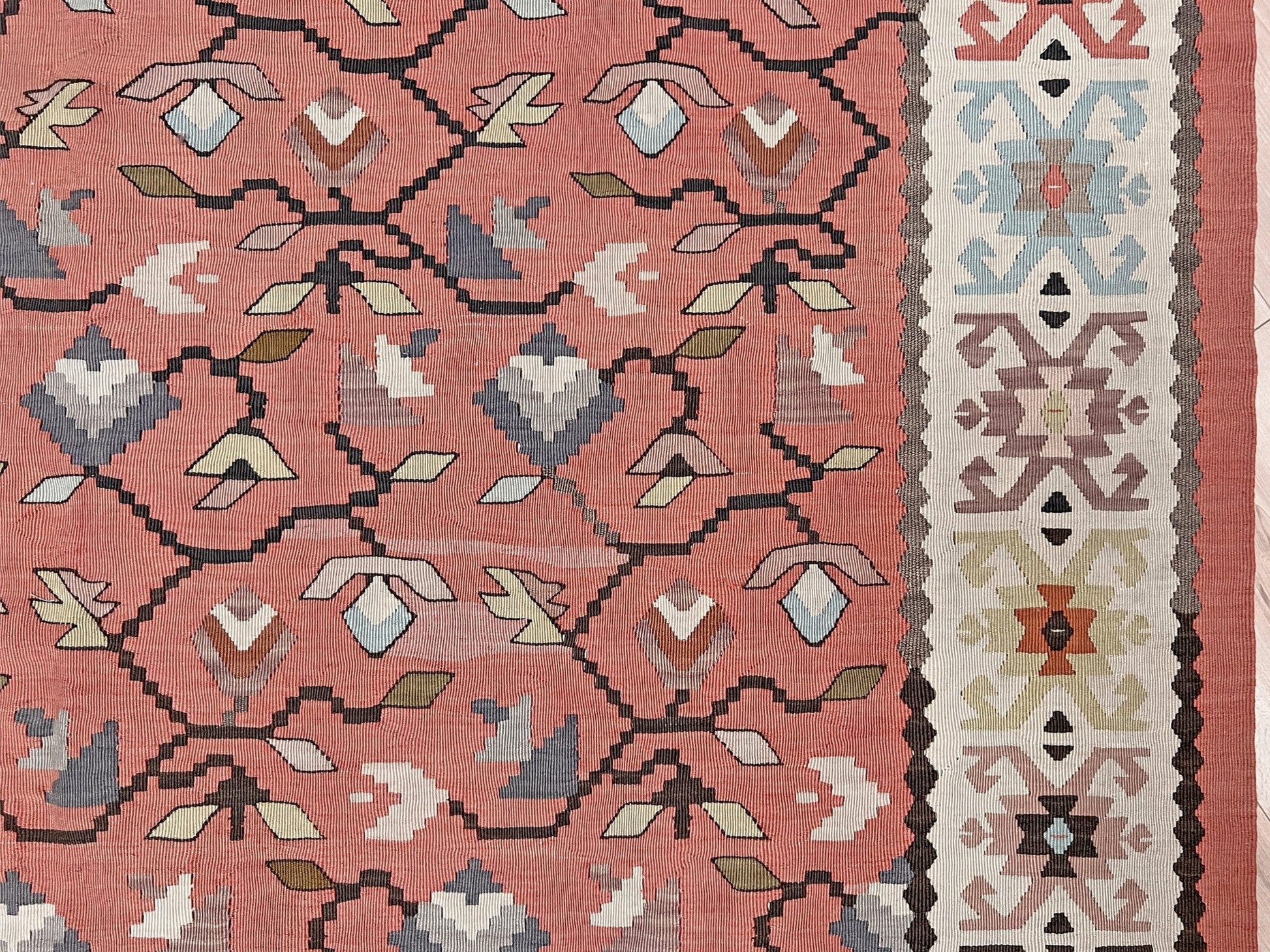 Vintage Balkan Pirot Sharkoy kilim rug, 5x8 with faded geometric floral motifs in dusty coral pink, ivory, sage, and soft blue tones with natural abrash.