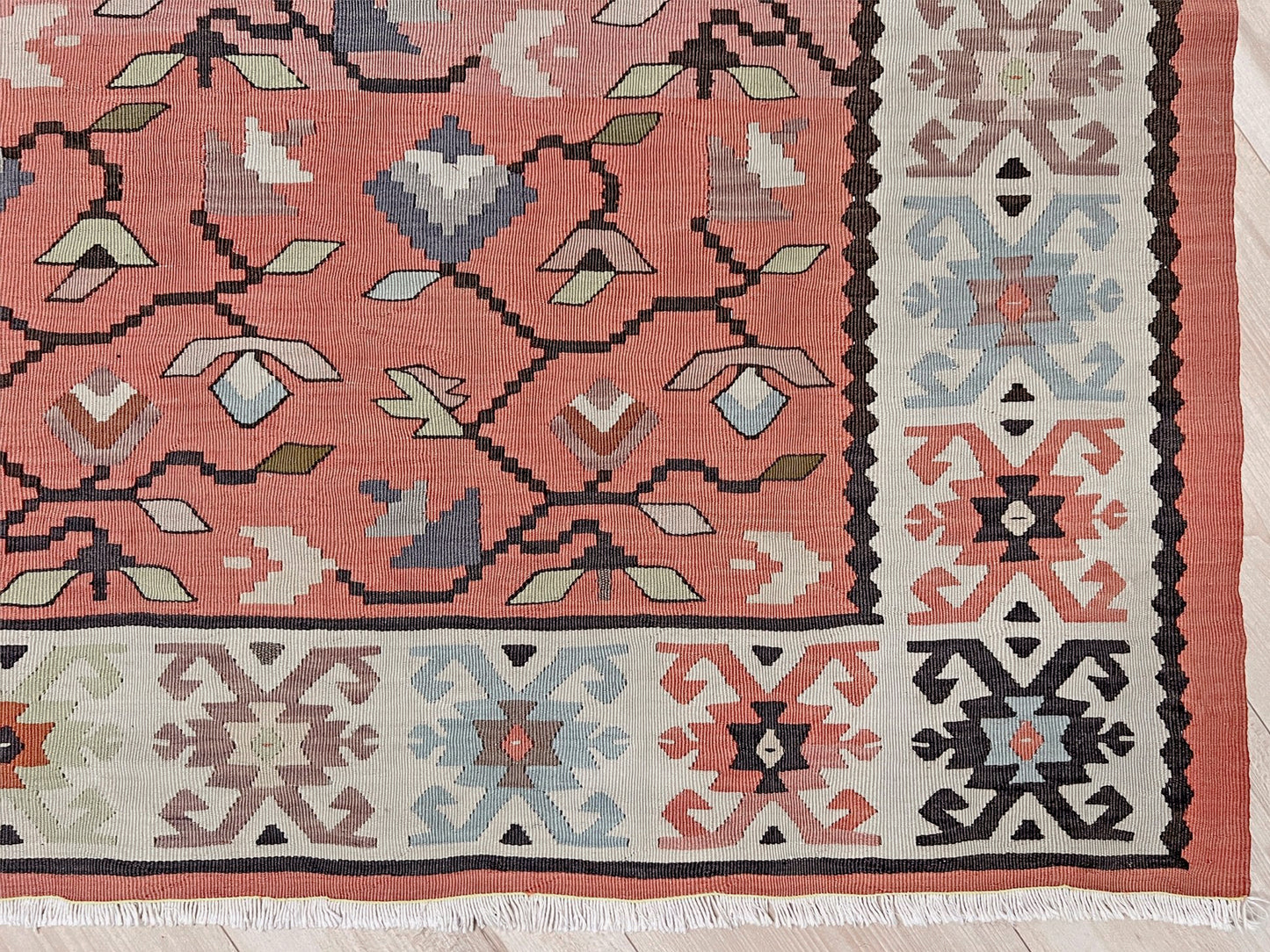 Vintage Balkan Pirot Sharkoy kilim rug, 5x8 with faded geometric floral motifs in dusty coral pink, ivory, sage, and soft blue tones with natural abrash.