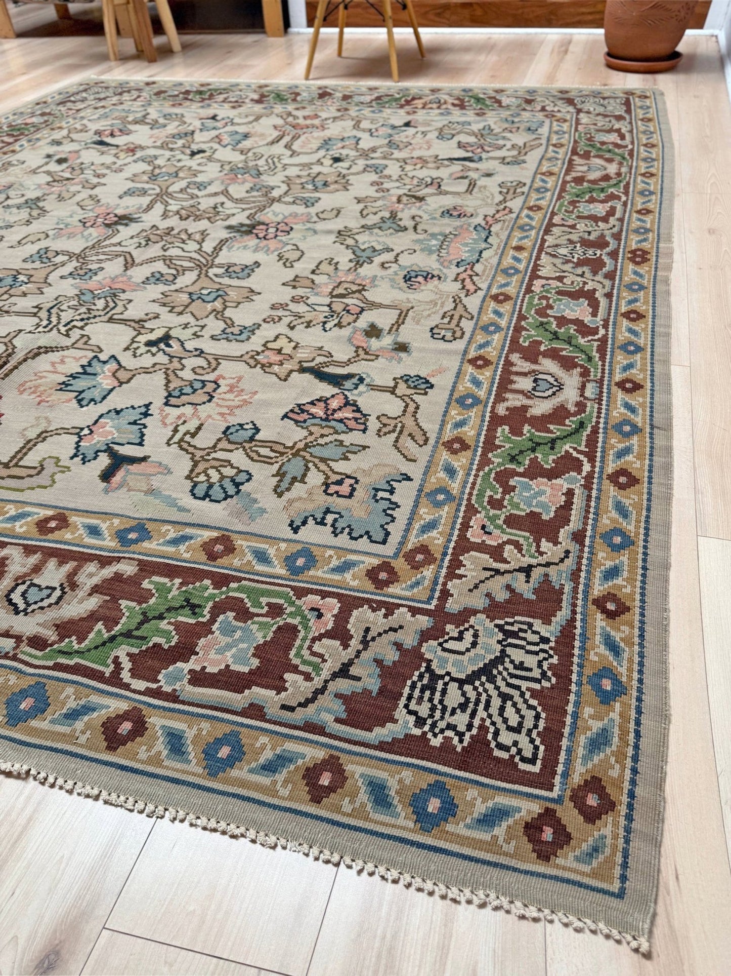 Handmade square 8x9 vintage Balkan floral kilim flatweave rug with light parchment field and vine-and-blossom design in dusty blue, rose, and sage tones.