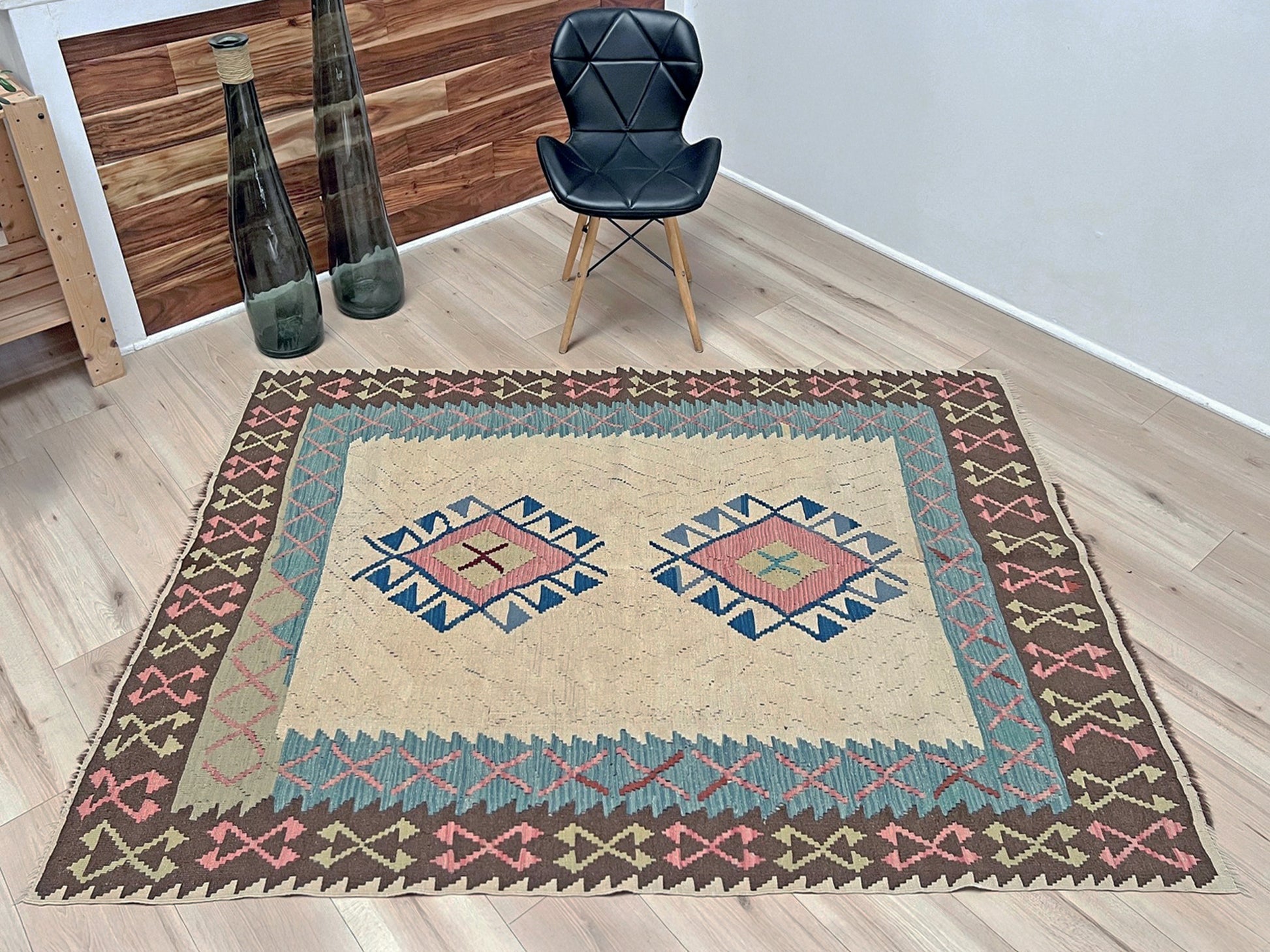 Decorative rug with geometric pattern featuring diamonds and cross symbols on a white background. Vintage Turkish kilim rug, 5x7, with ivory field, pink and blue tribal medallions, and geometric borders in brown and sage tones.