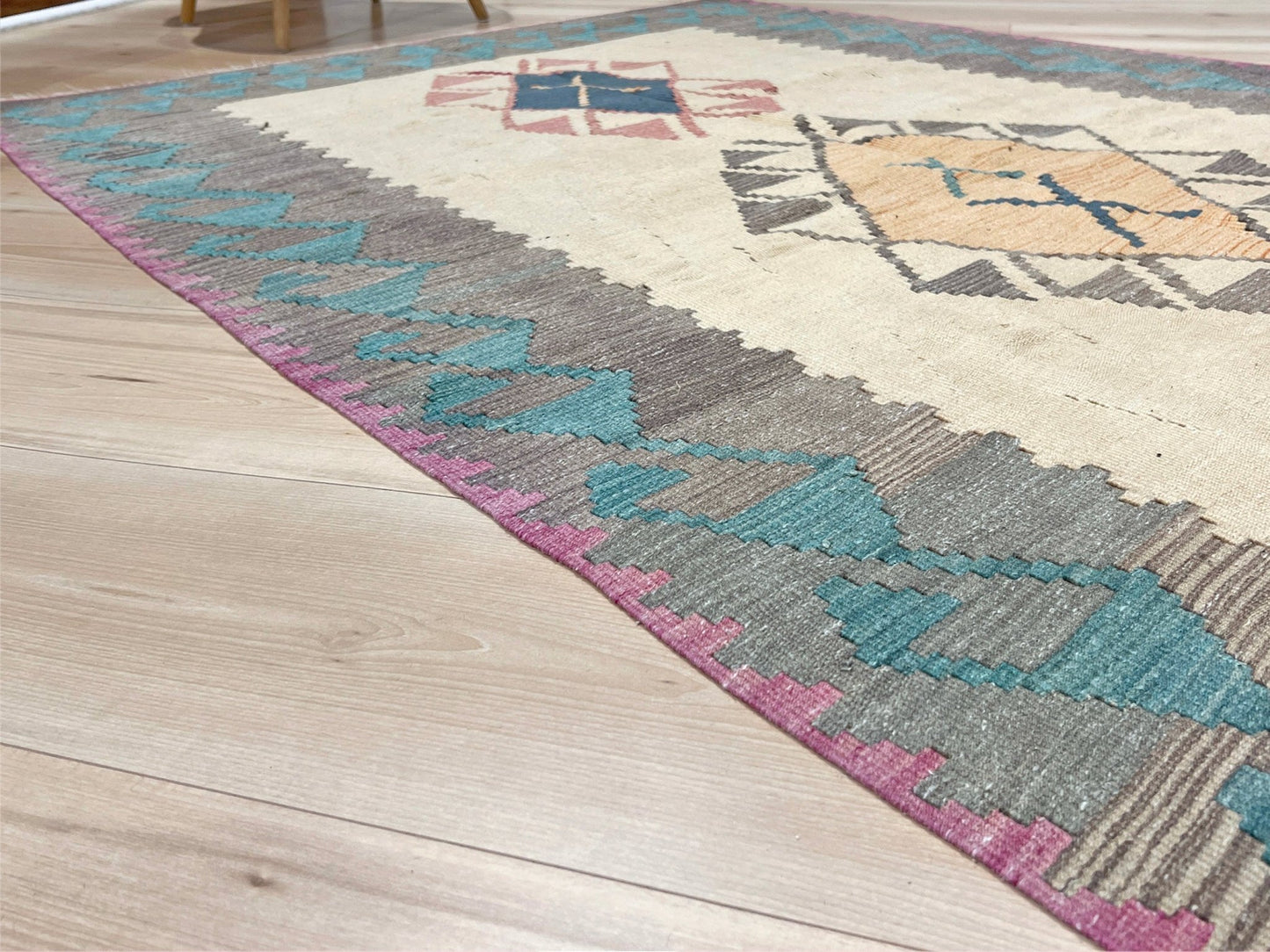 Decorative rug with geometric pattern featuring diamonds and cross symbols on a white background. Vintage Turkish kilim rug, 5x7. 