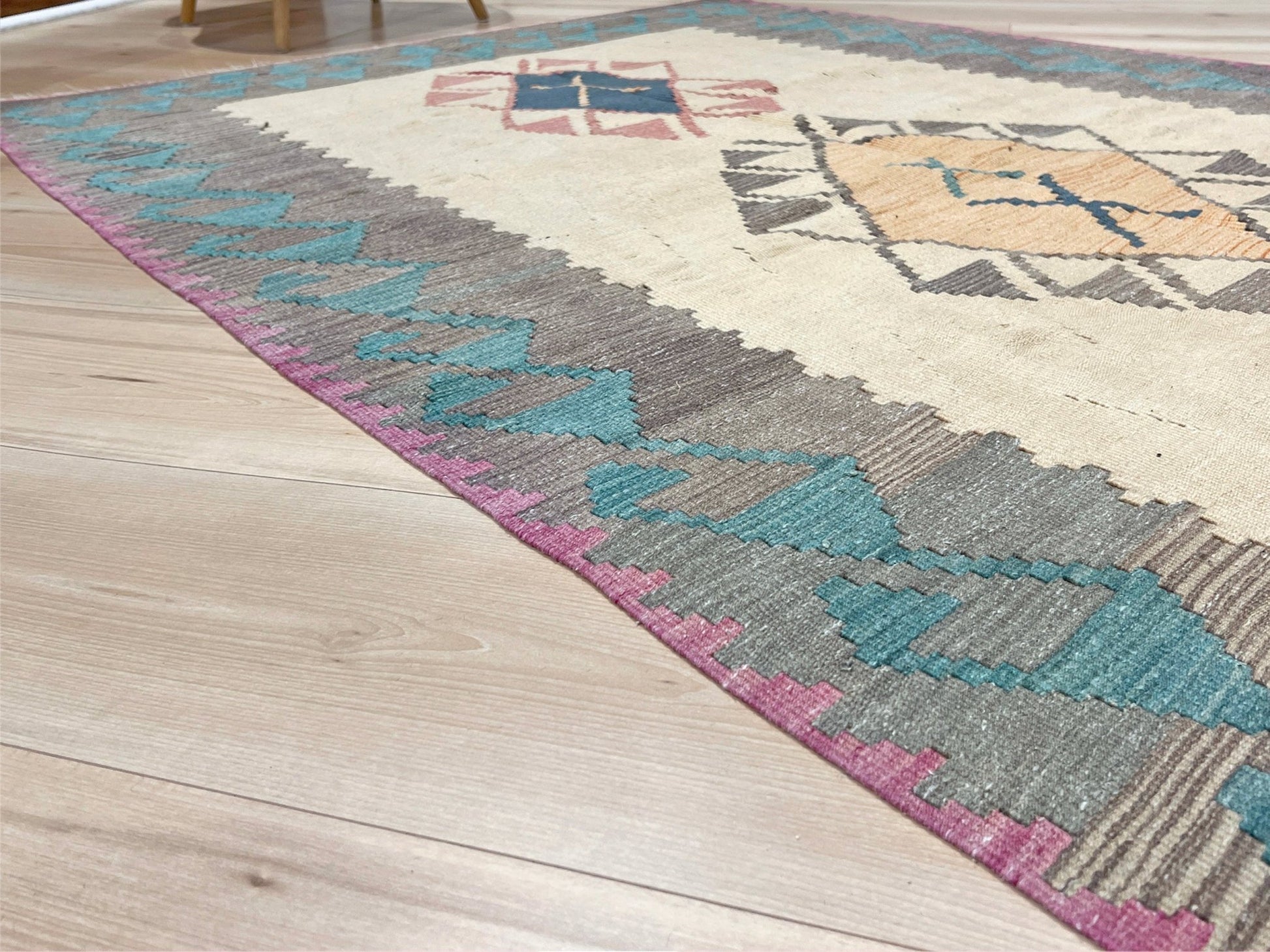 Decorative rug with geometric pattern featuring diamonds and cross symbols on a white background. Vintage Turkish kilim rug, 5x7. 