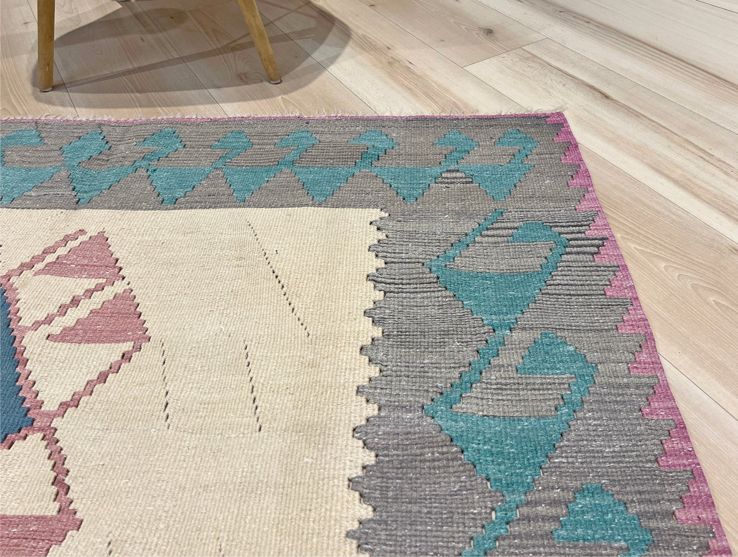 Decorative rug with geometric pattern featuring diamonds and cross symbols on a white background. Vintage Turkish kilim rug, 5x7. 