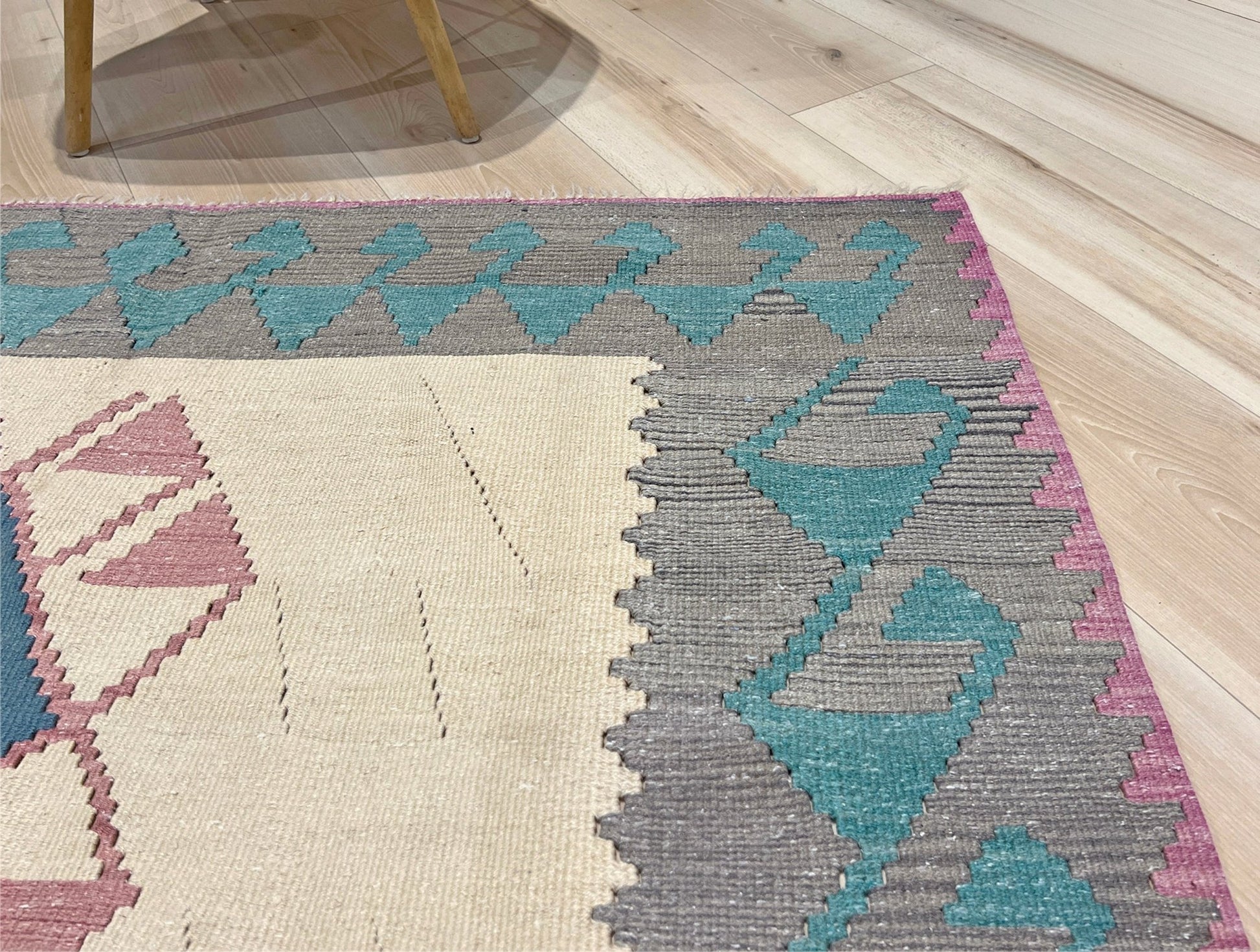 Decorative rug with geometric pattern featuring diamonds and cross symbols on a white background. Vintage Turkish kilim rug, 5x7. 