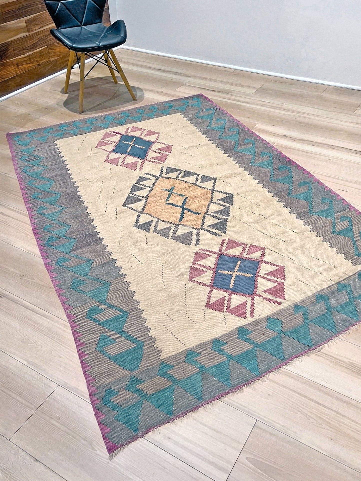 Decorative rug with geometric pattern featuring diamonds and cross symbols on a white background. Vintage Turkish kilim rug, 5x7. 